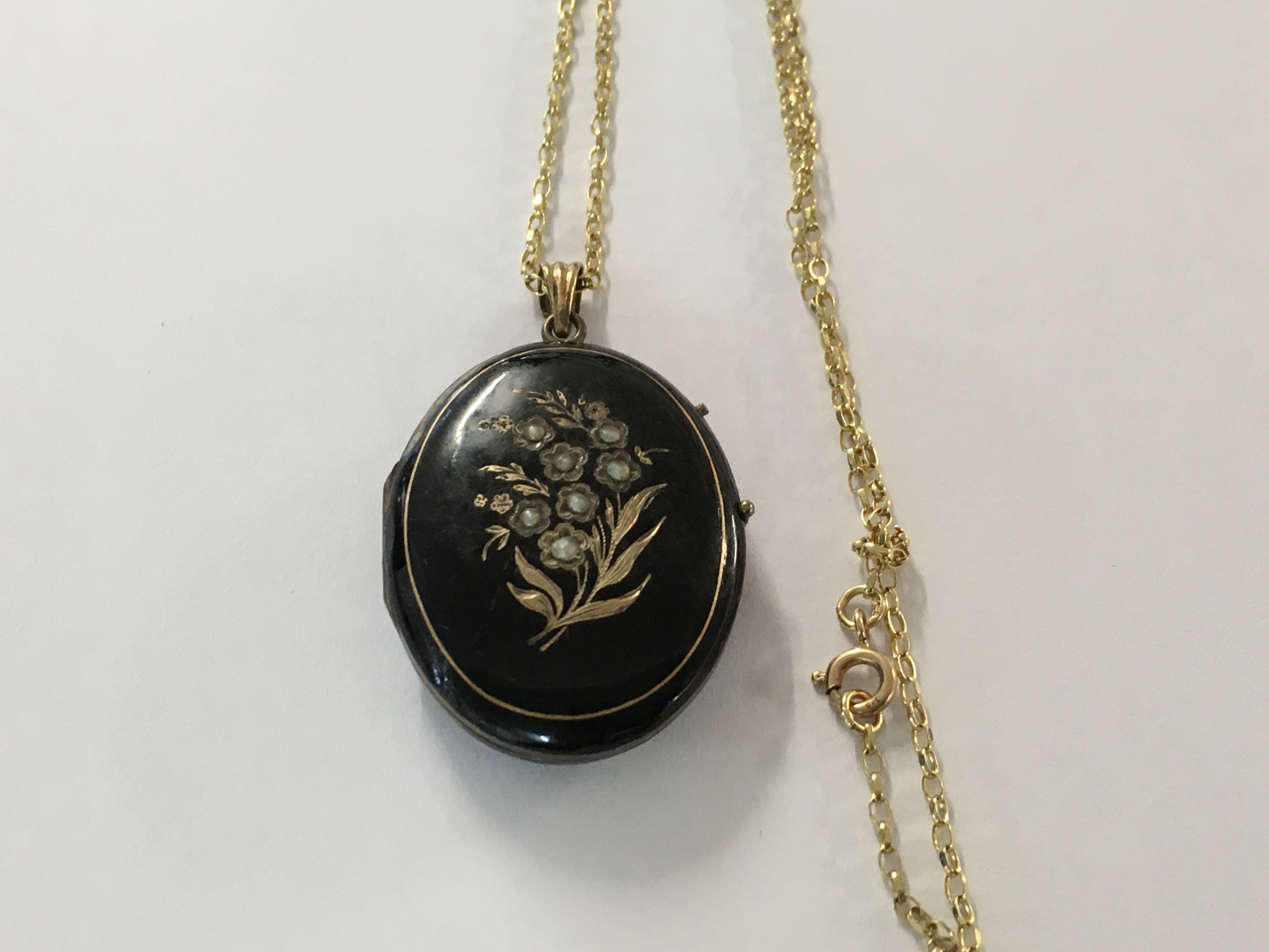A Victorian locket inset with seed pearls with attached 9 ct gold chain.