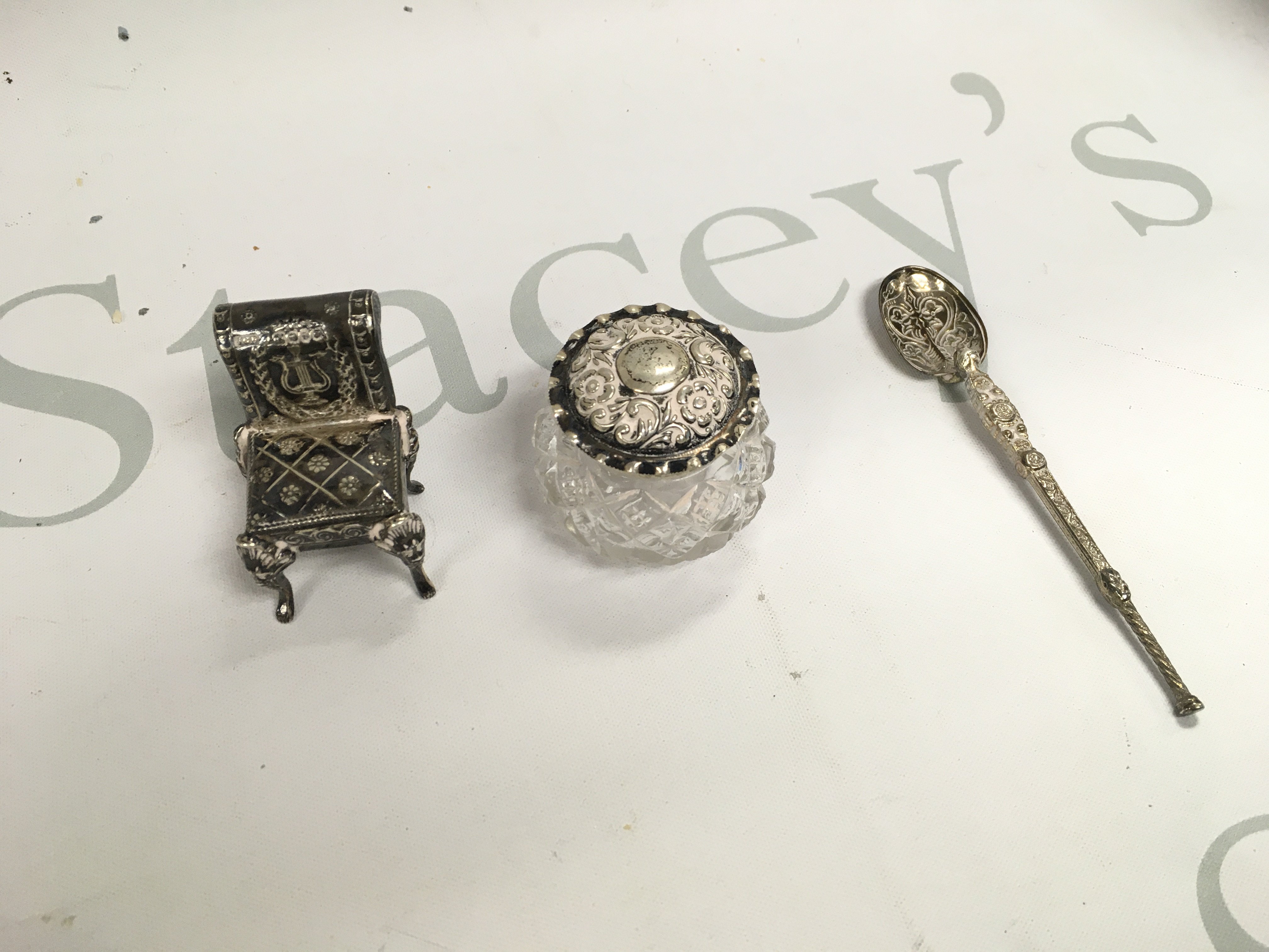 A small collection of silver including a miniature chair a spoon and a jar.