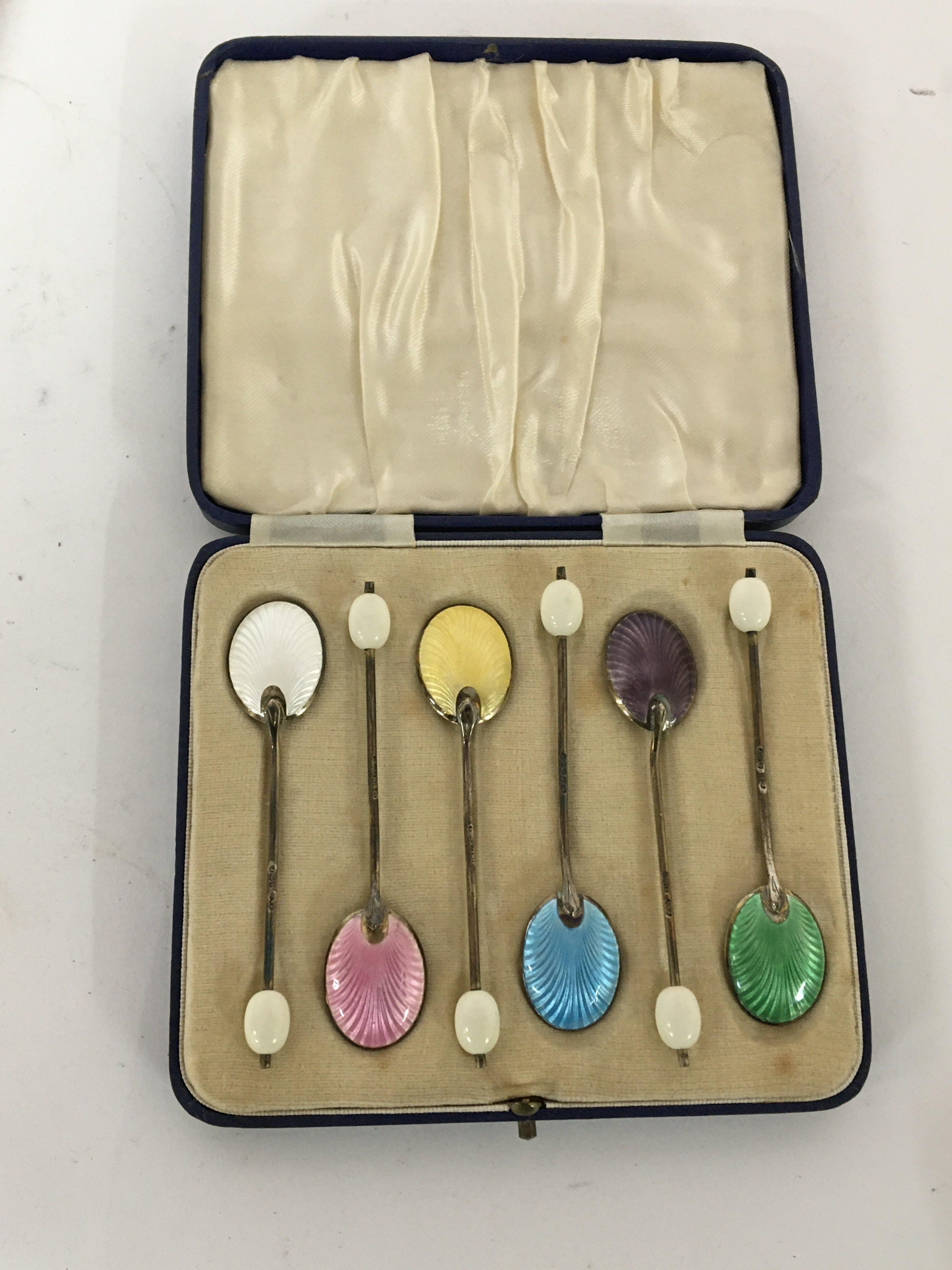 A cased set of silver and enamel coffee spoons.