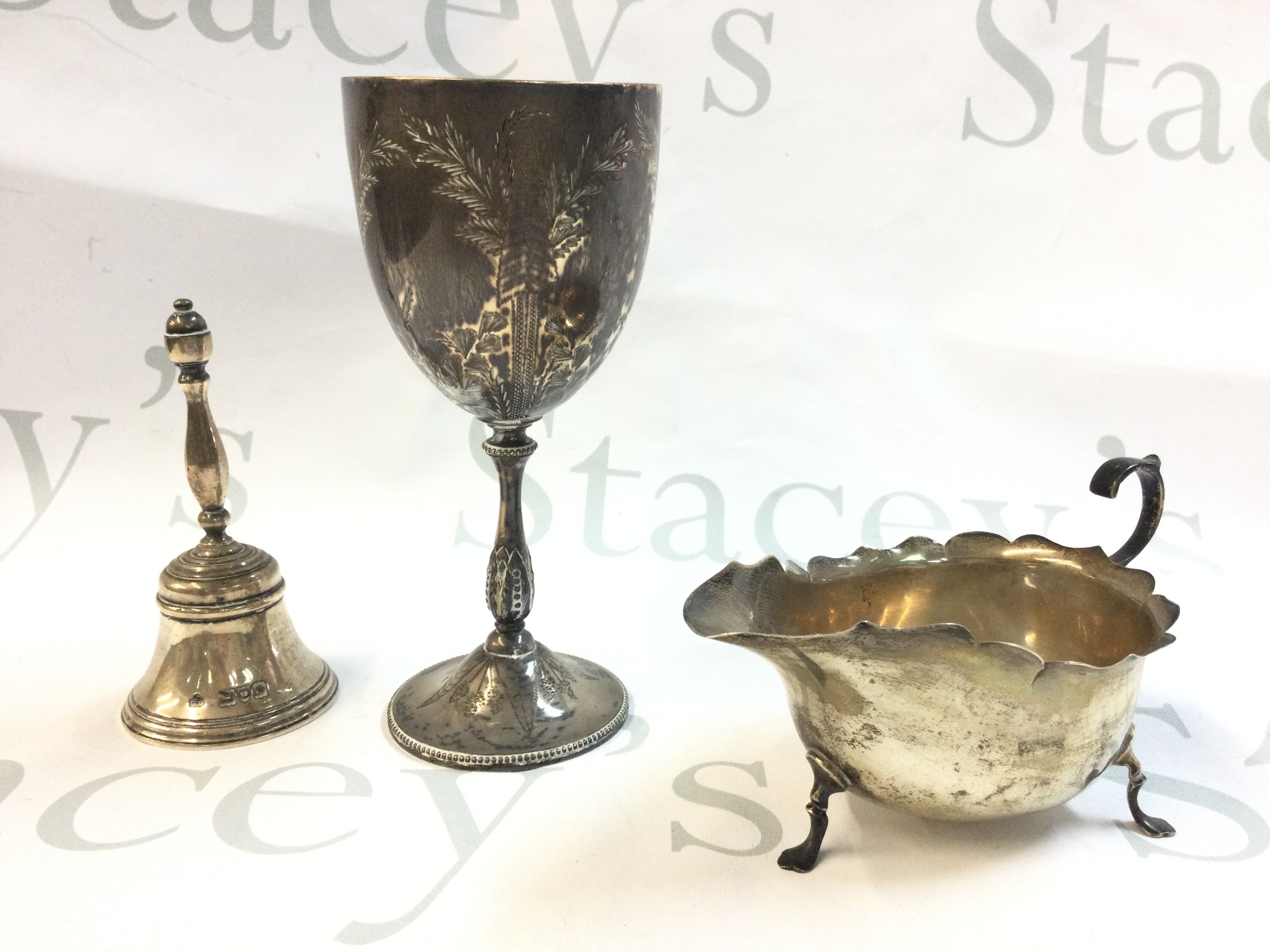 A collection of silver hallmarked items including a pair of silver fruit serving spoons marked Edinburgh 1796, gravy boat , Goblet and a bell. Total weight approximately 510g Postage category B