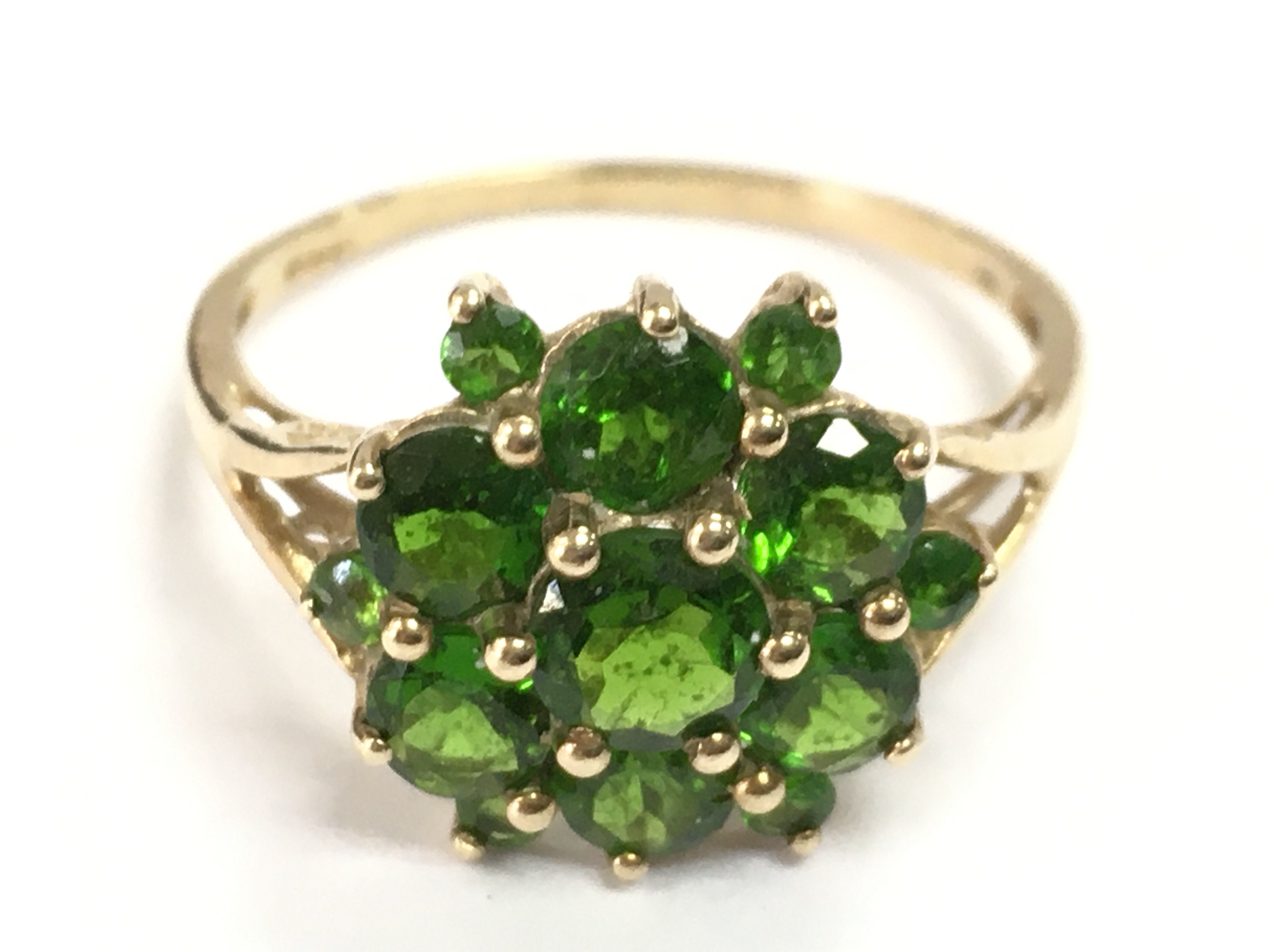 A 9 carat gold ring set with green gemstones , 2.6g total weight . Postage category A