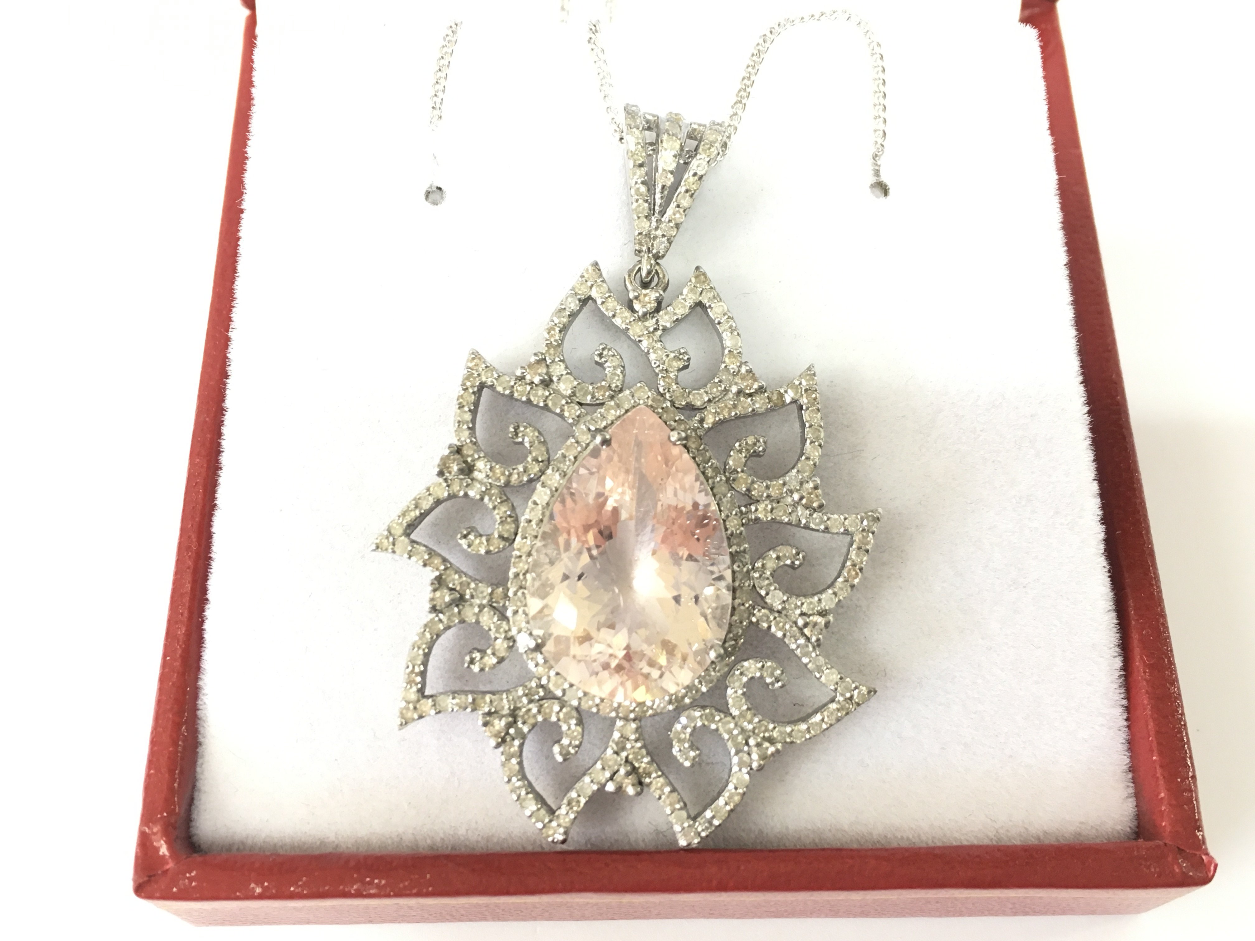 A silver pendant set with pear shaped morganite and diamonds in an ornate setting on a silver chain. Morganite 8.80ct and 1.51ct diamonds. Postage B