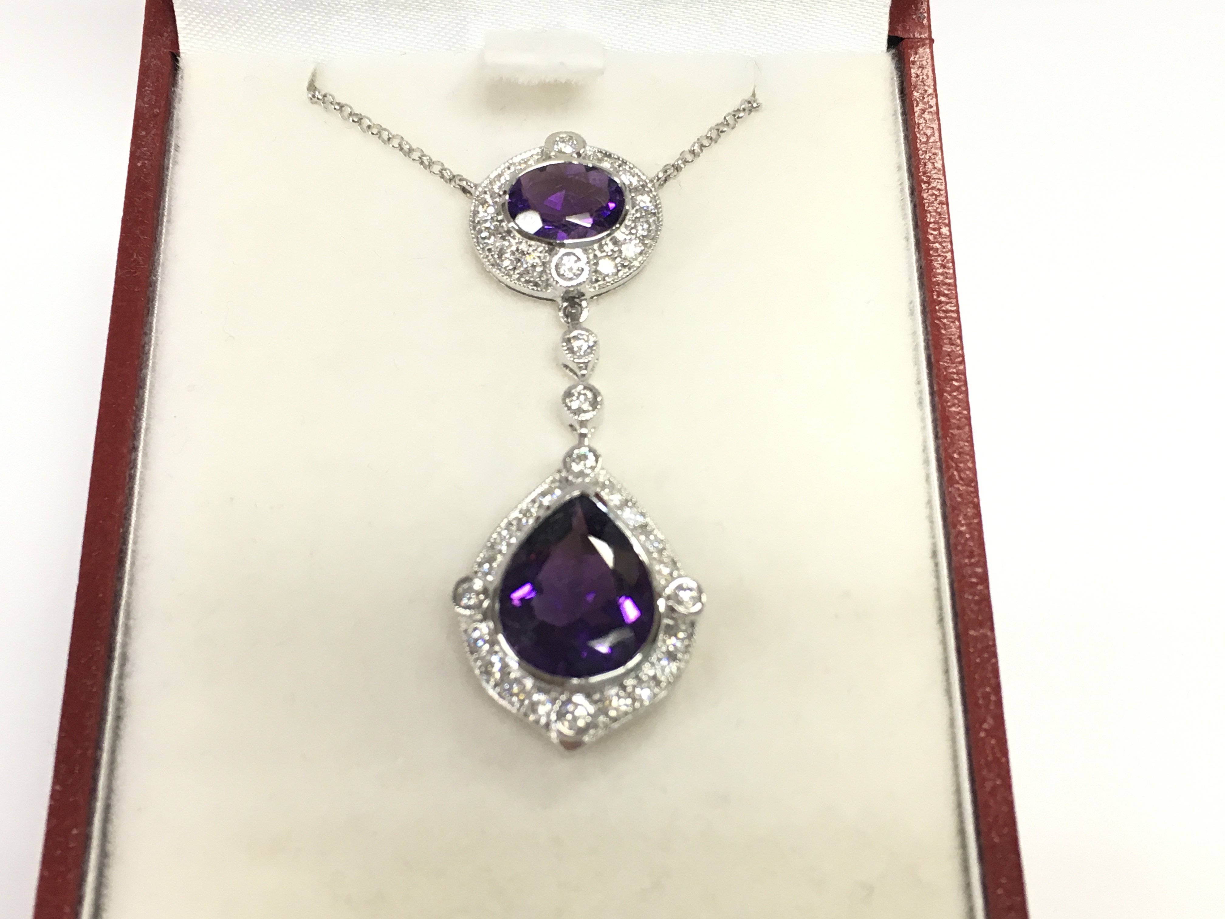 18ct white gold pendant set with a pear shaped amethyst an oval amethyst and RBC diamonds. Amethyst 4.23ct and diamonds 0.66ct. Postage B