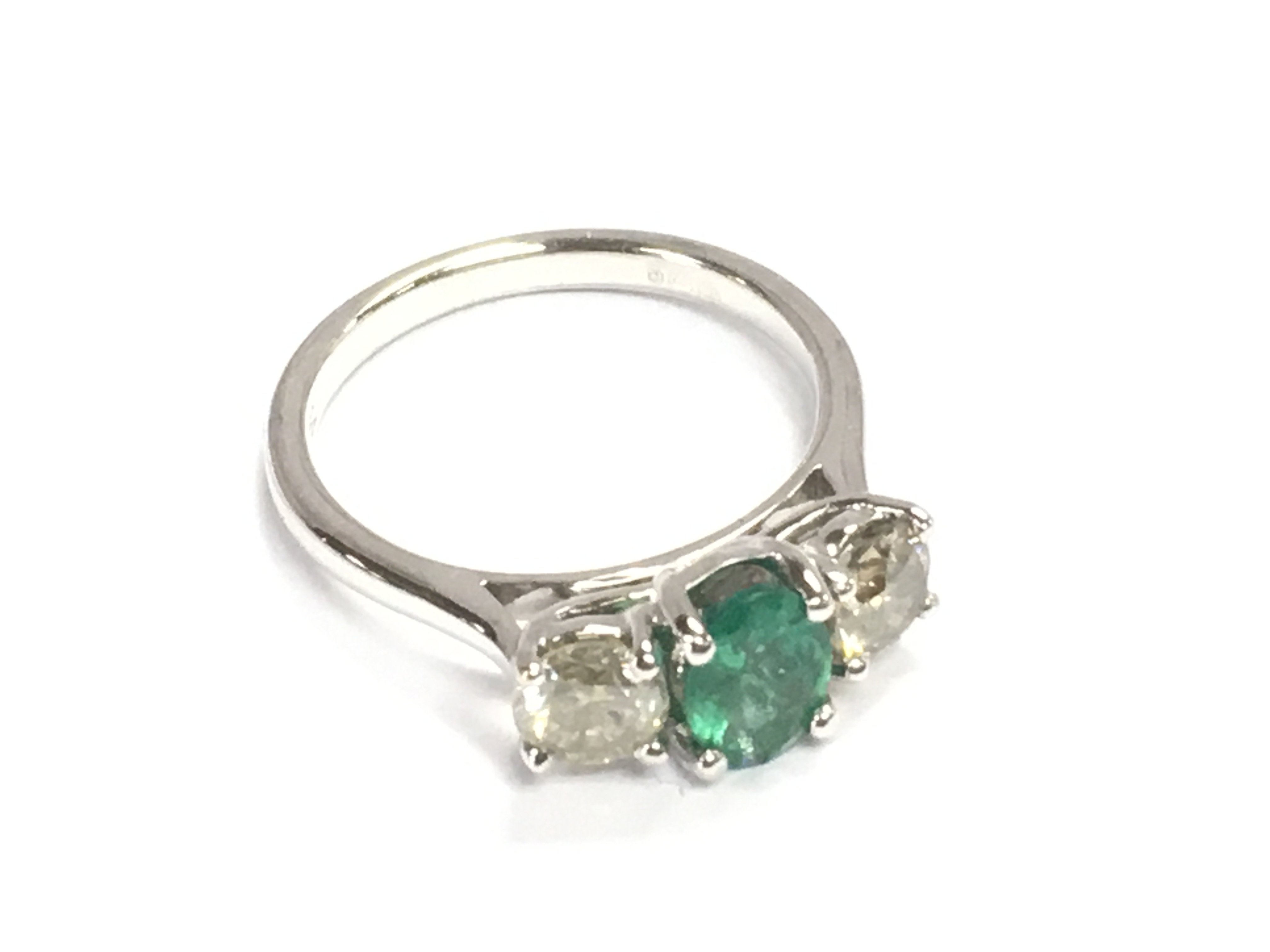An 18ct white gold emerald and diamond trilogy ring. Emerald 0.66ct and diamonds 0.37ct size M. Comes with gem cert.