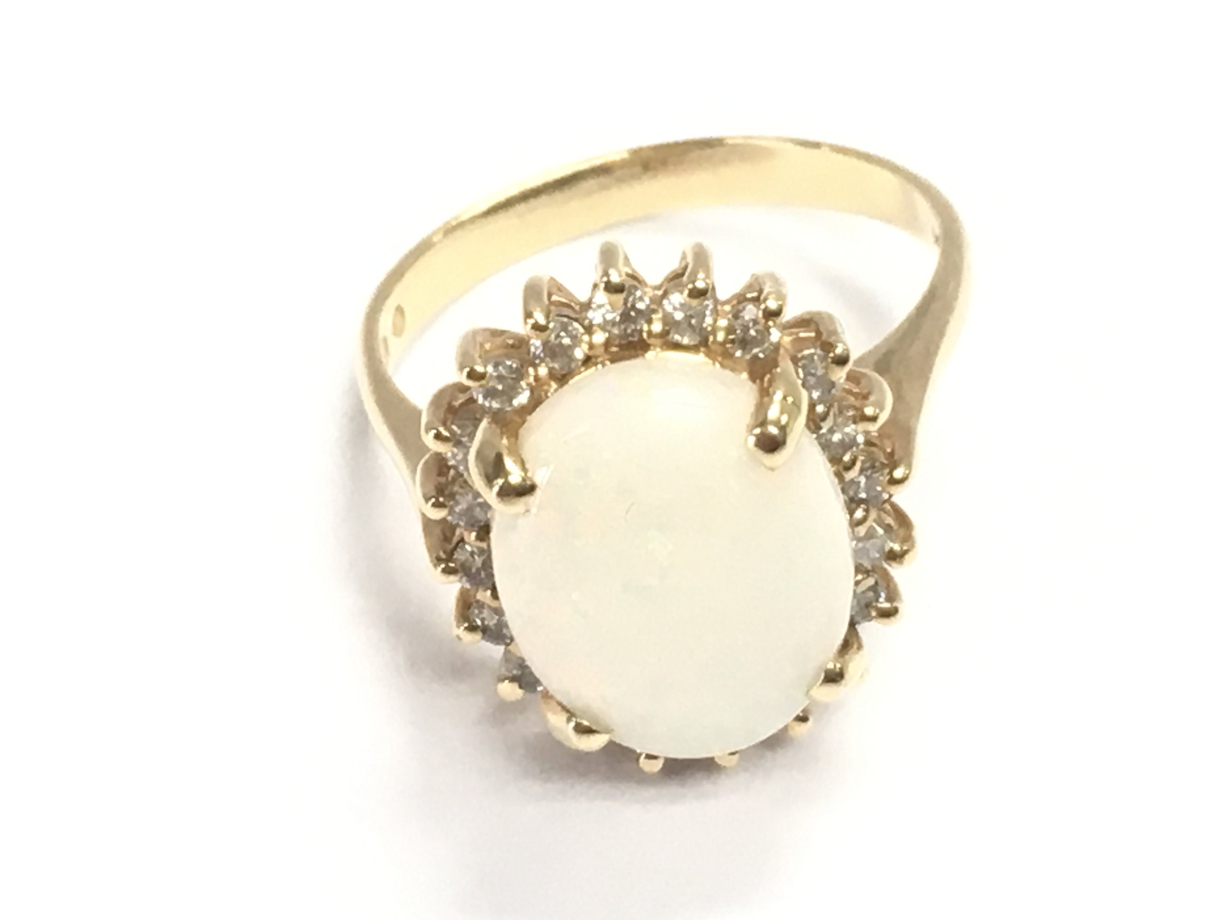 Traditional style 14ct yellow gold cluster ring set with an oval cabochon white opal surrounded by a halo of RBC diamonds. Approximately 2ct opal and 0.20ct diamonds. Size m 1/2