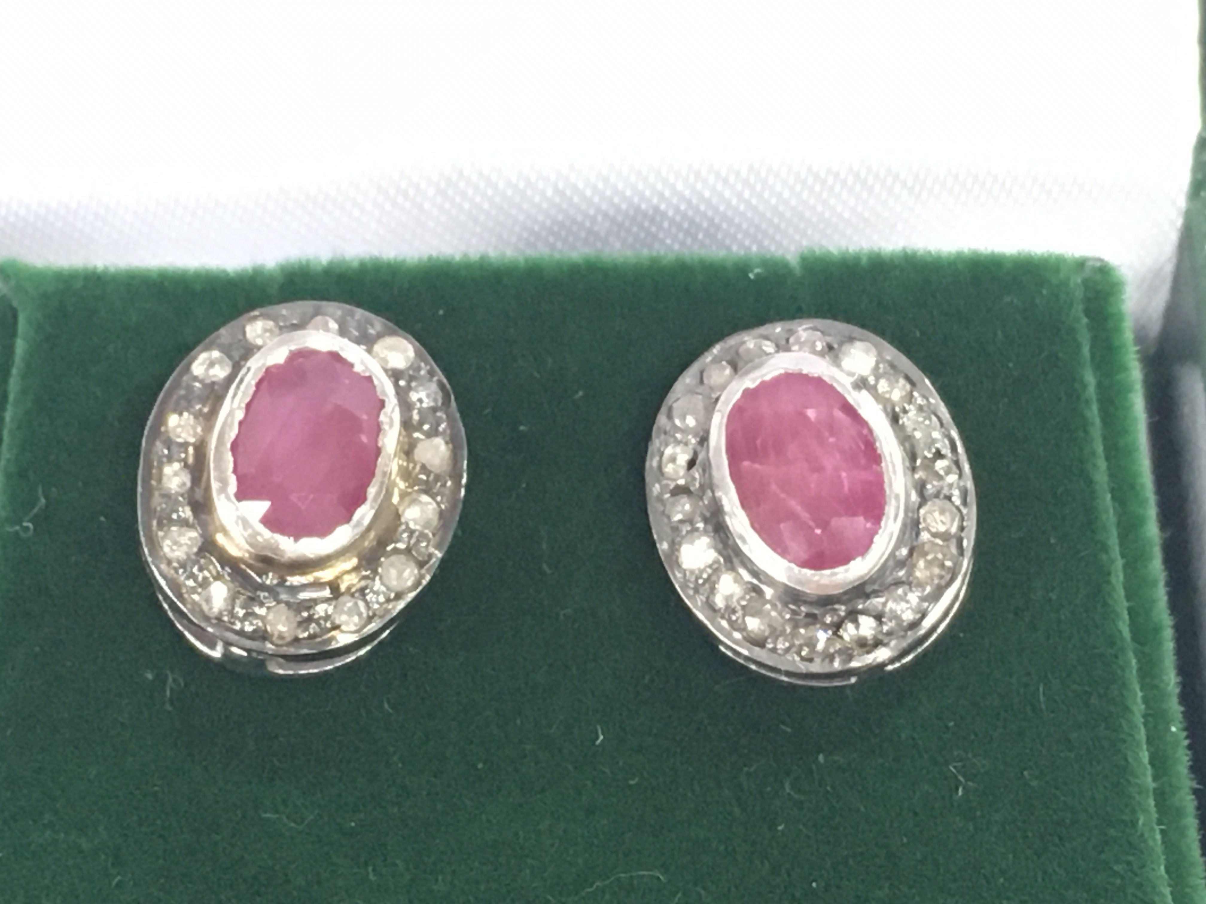 A pair of oval ruby and RC diamond halo studs set in gold plated silver. Approximately 0.45ct rubies and 0.28ct diamonds.