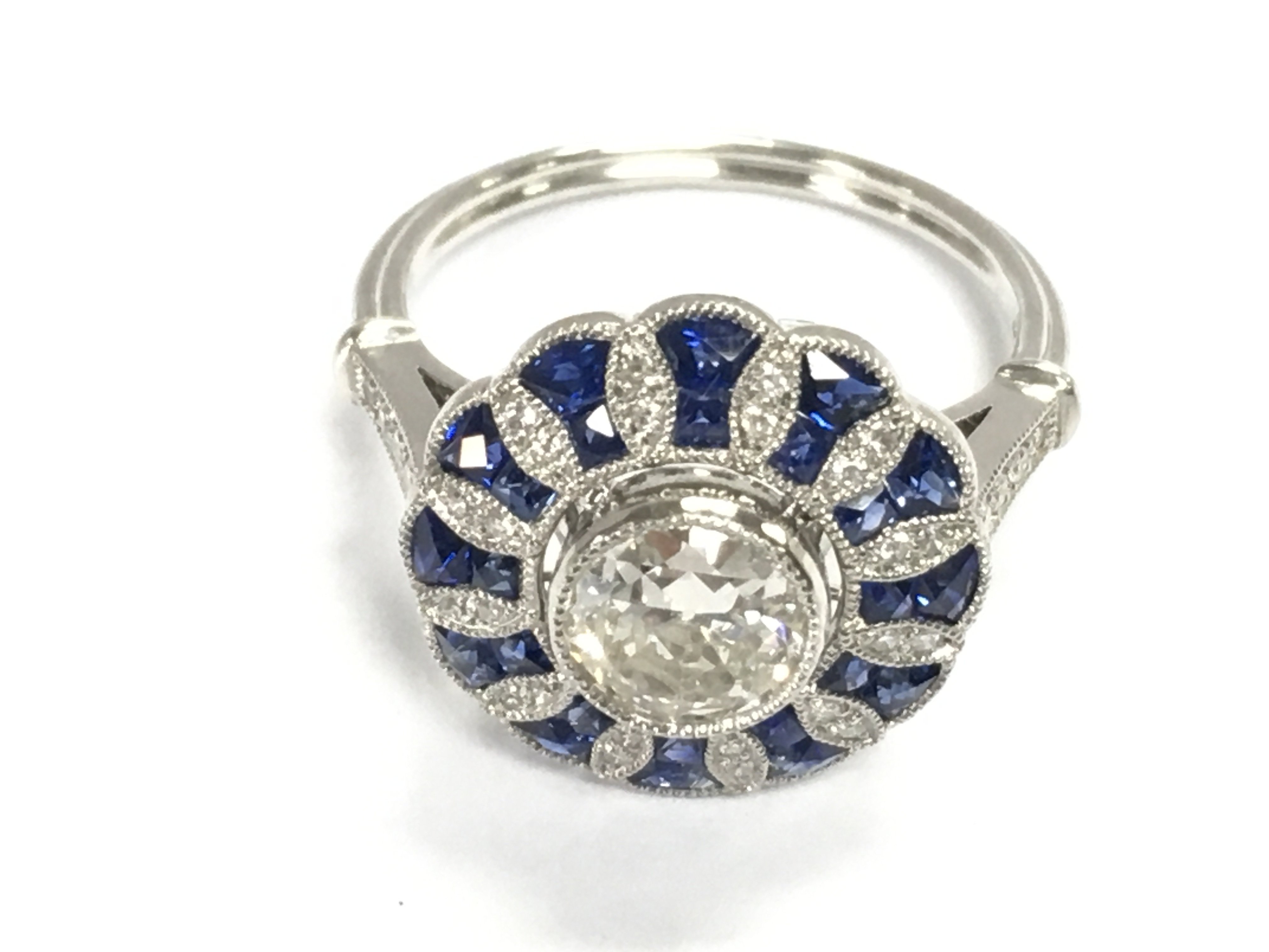 A stylish platinum target ring set with a central RBC diamond surrounded by mixed cut sapphires and RC diamonds. Centre diamond 0.79ct and sapphires 0.85ct remaining diamonds approximately 0.10ct. Size N 1/2