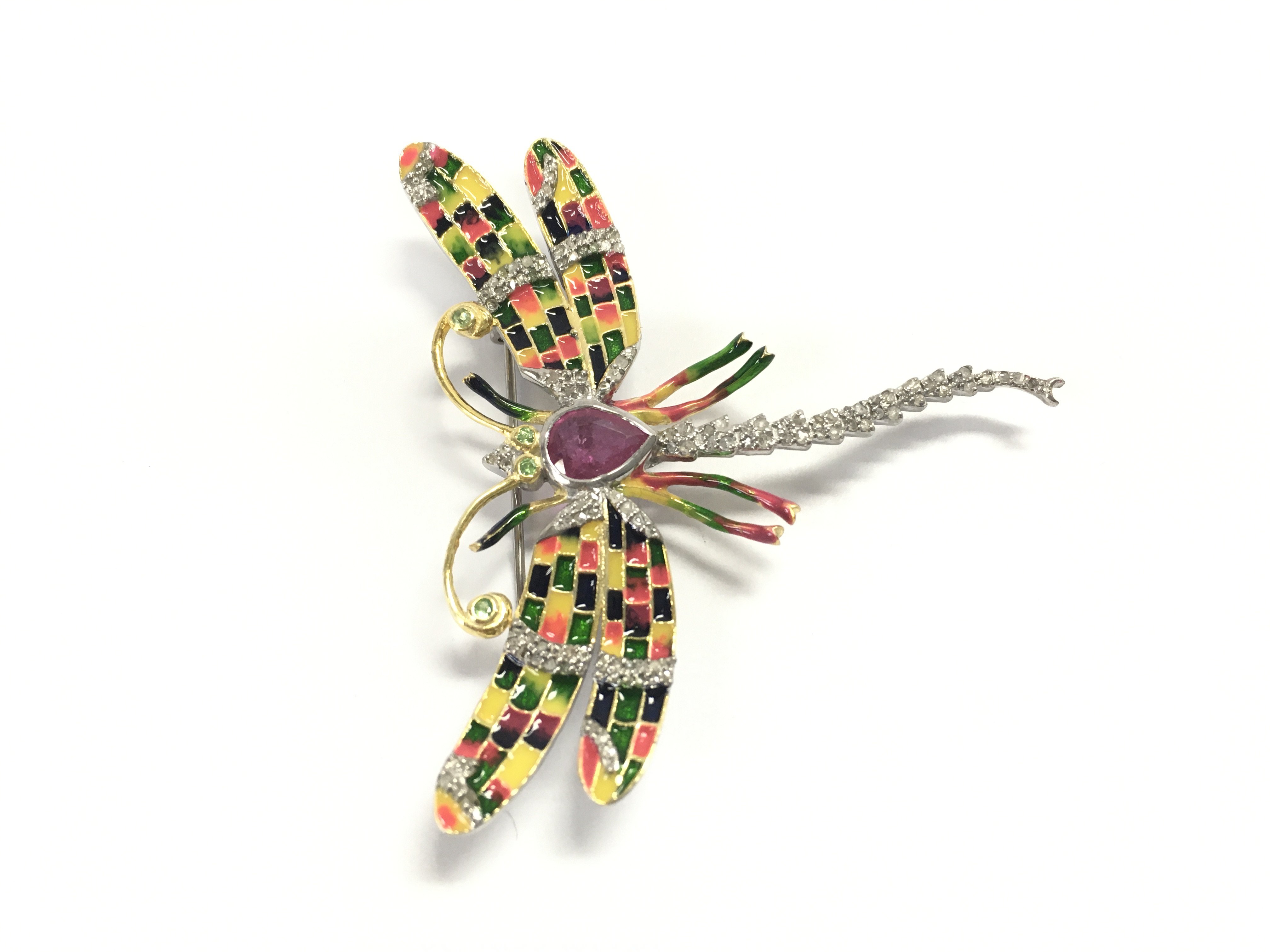 A silver dragonfly brooch / pendant set with a pear shaped ruby tsavorite garnet eyes and antennae and diamonds with enamel inlays on yellow pink blue orange and green. Ruby 1.19ct diamonds 0.52ct and 0.08ct garnets.
