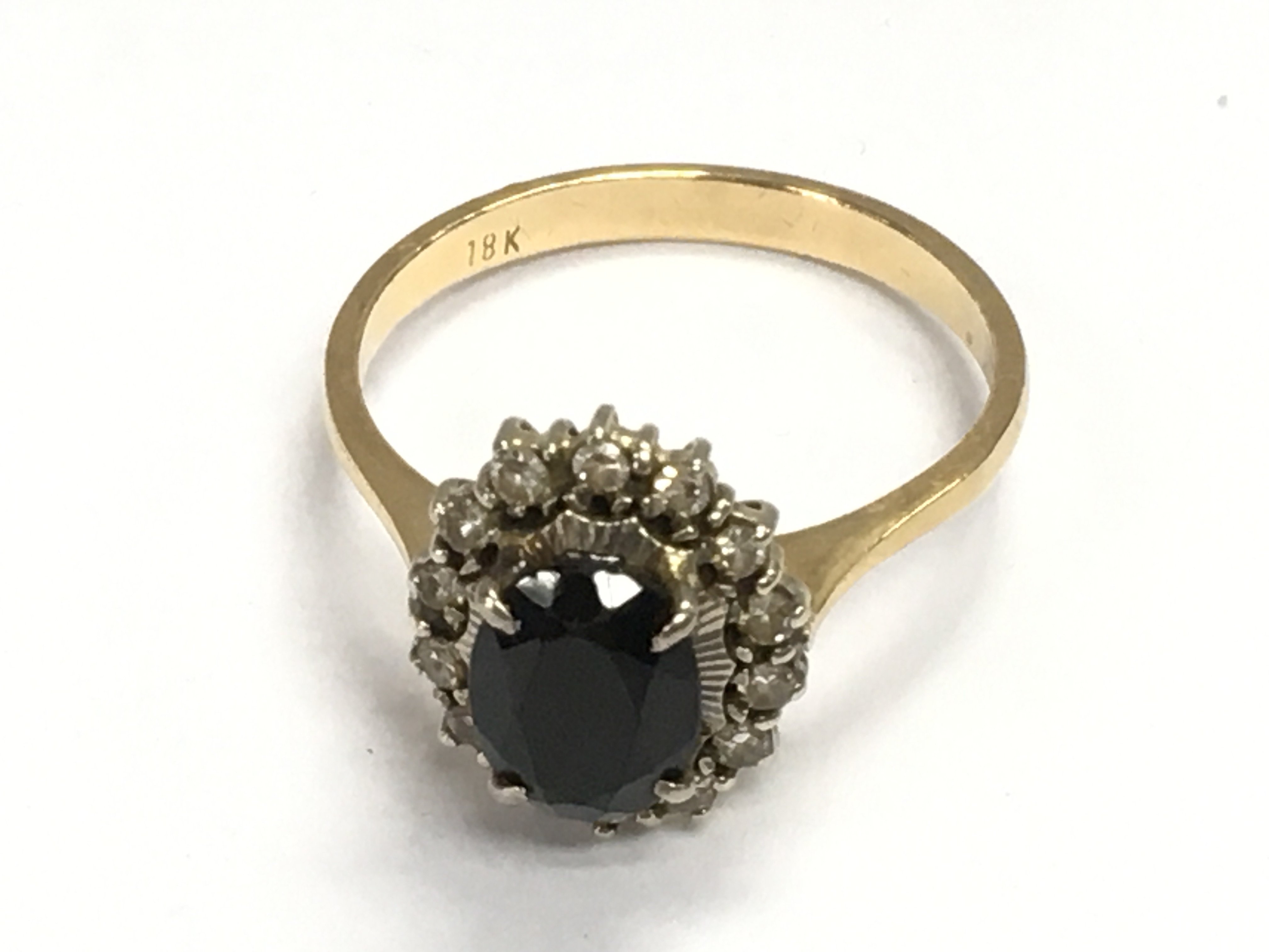 An 18ct gold ring set with a deep green Tourmaline approximately 1.3ct flanked by 14 diamonds. Size O 1/2 and 3.68g