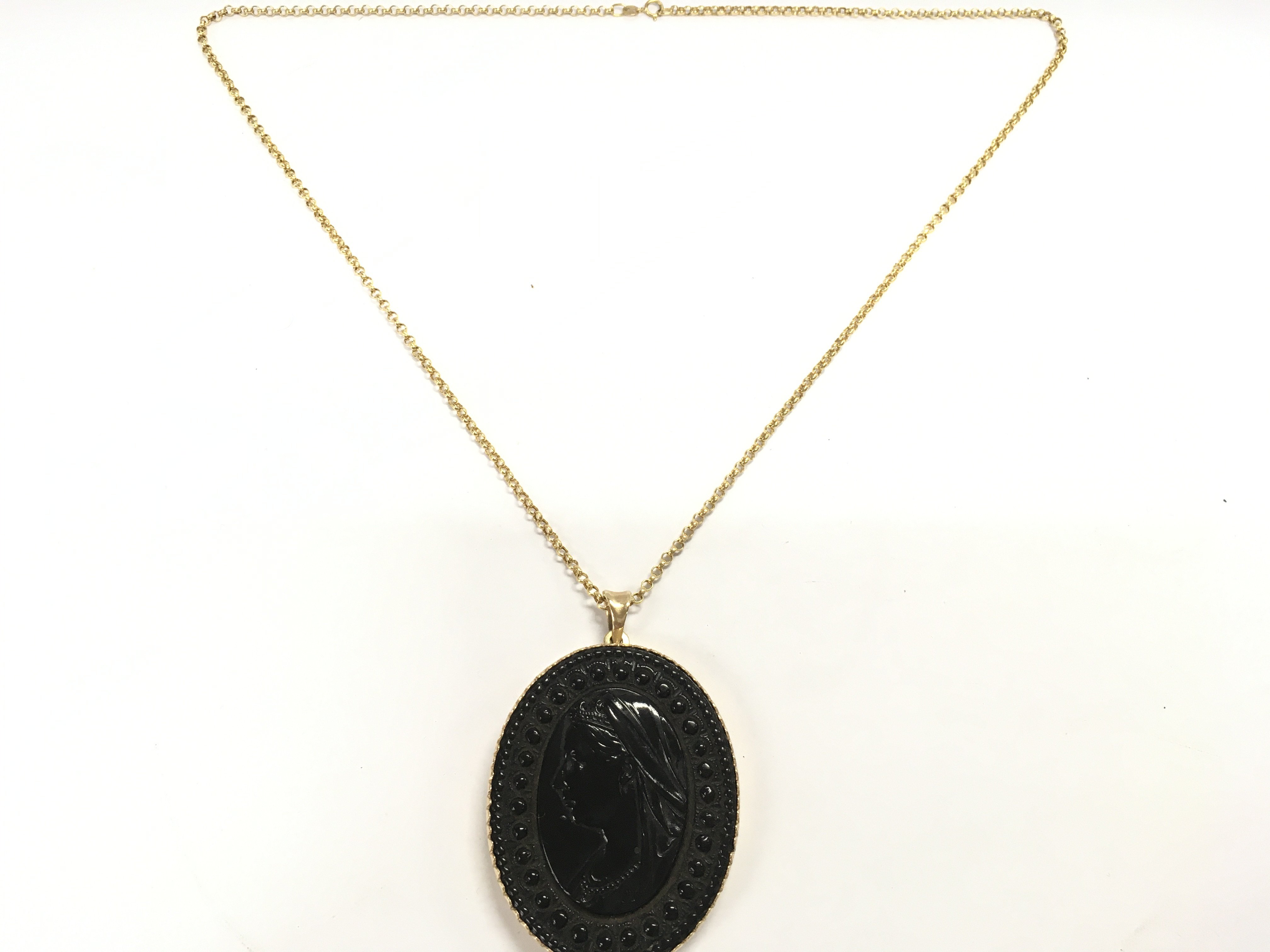 A Victorian jet oval pendant set in a 9ct gold frame on a 9ct gold chain. Postage B