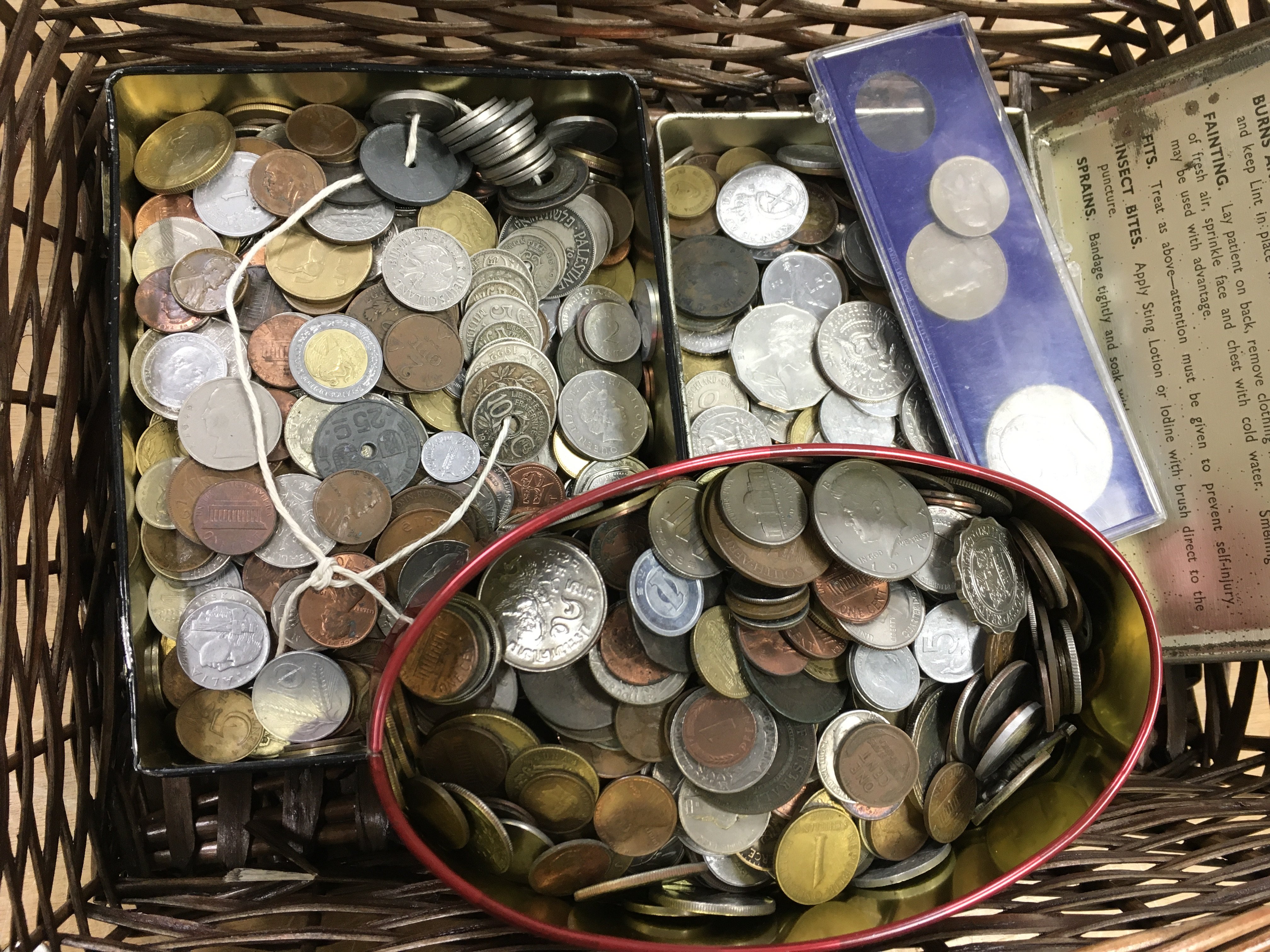 Three tins of assorted foreign coinage.