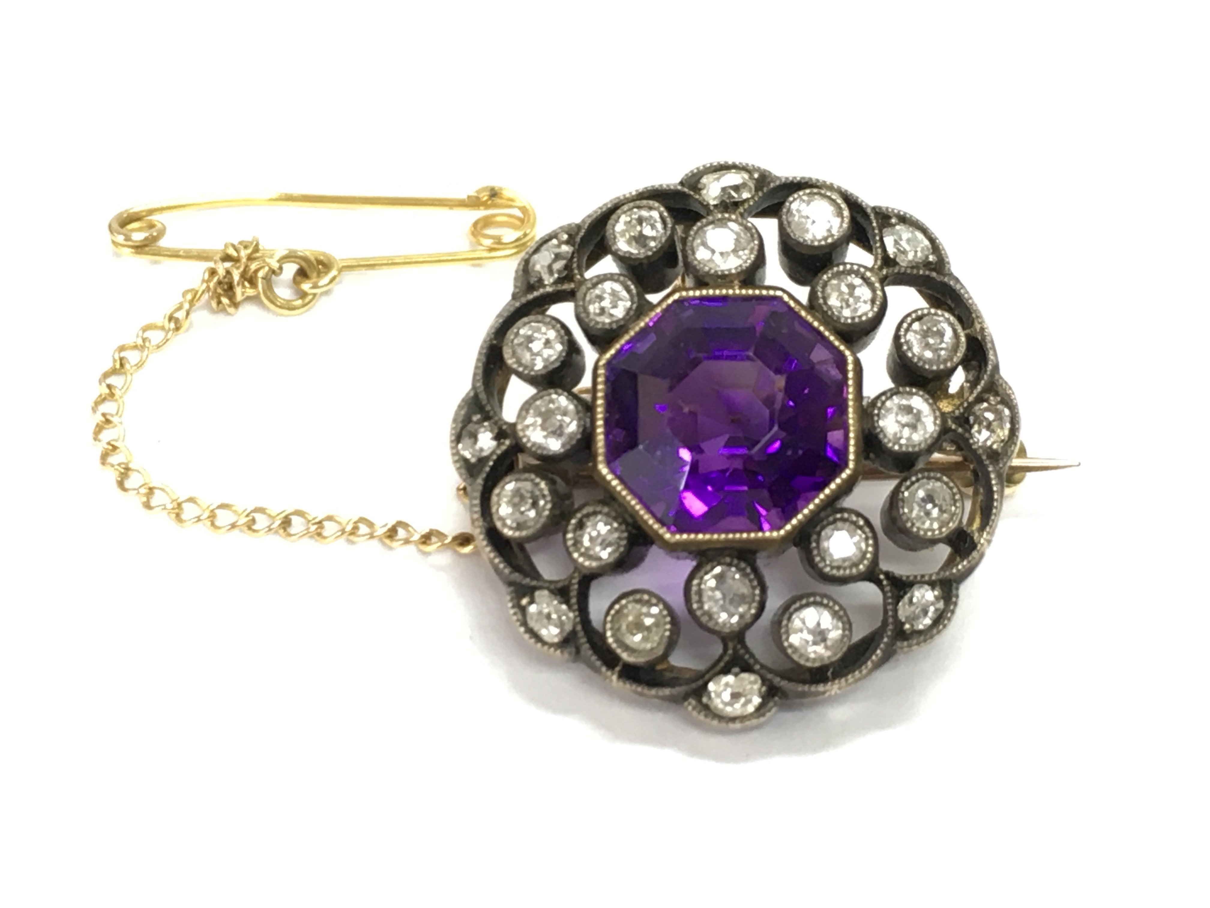 A gold and silver diamond and amethyst set brooch. Diameter approximately 20mm and 6g Postage B