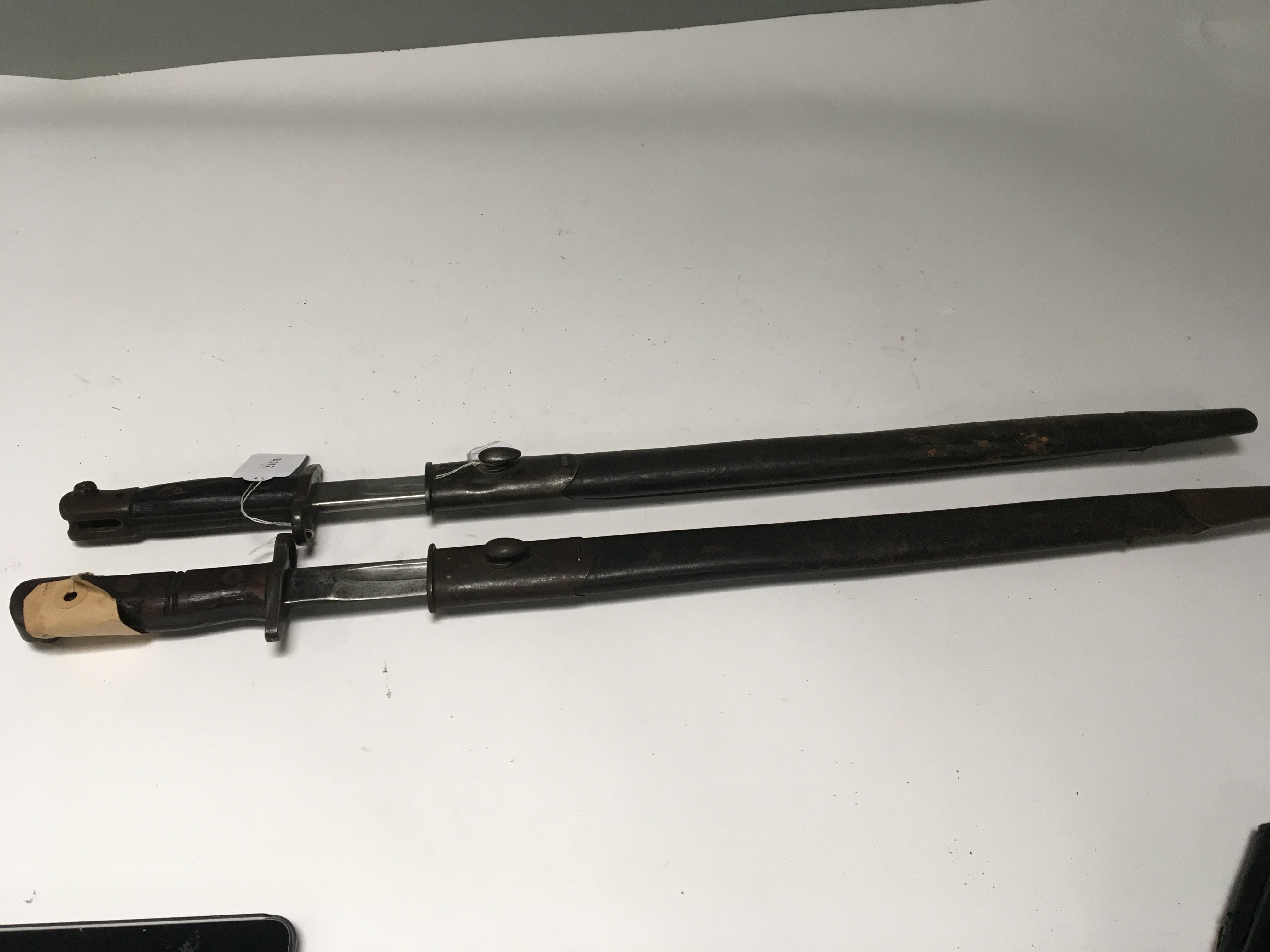 Two British Military bayonets early 20th century made by Wilkinson 1907 both with the crown stamp makers stamp and other military record stamps to the blade leather scabbards with metal fittings (2)