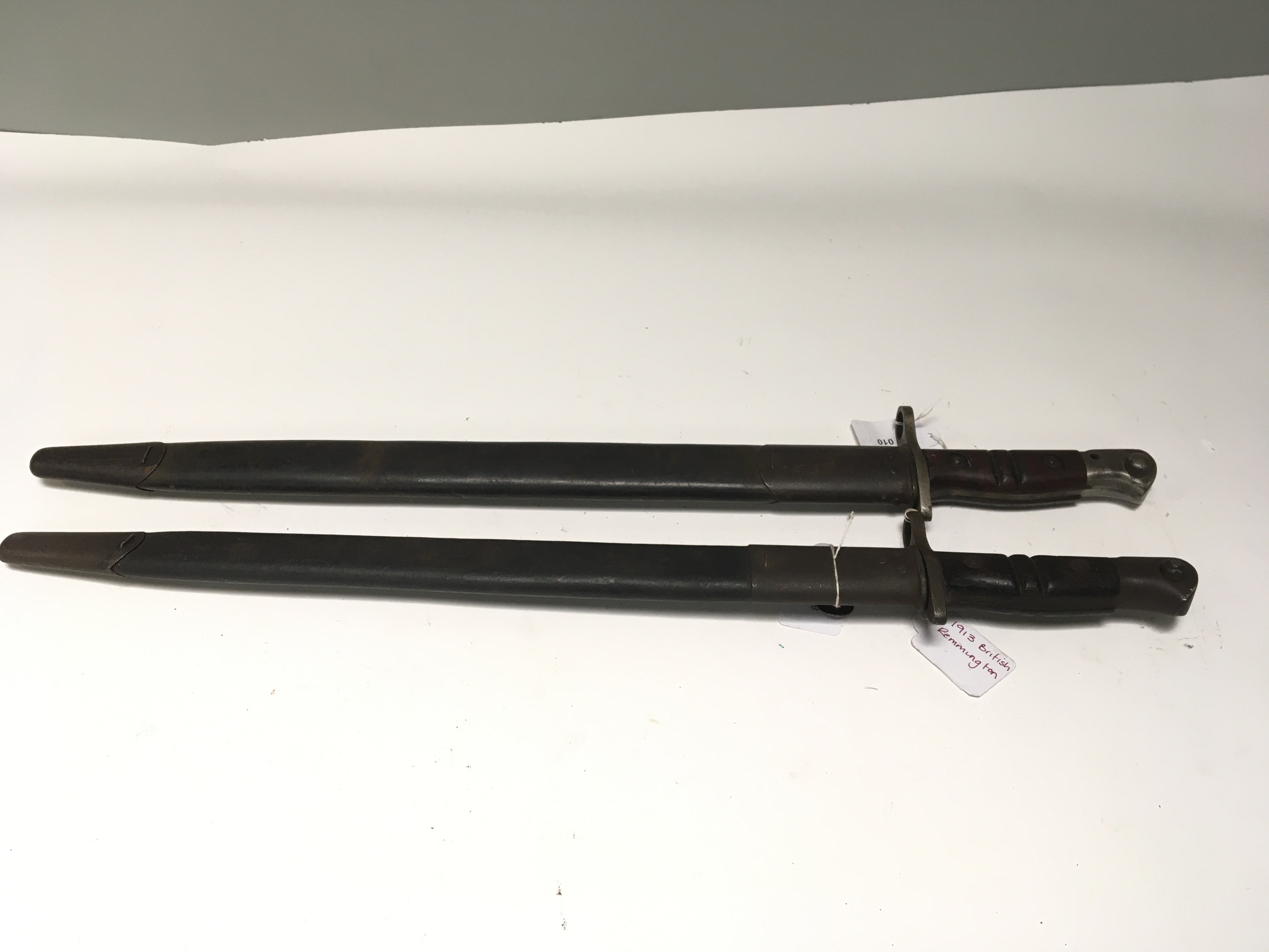 Two I world war Remington bayonets one stamped 1913 with British military issue reference marks to the blade the other stamped 1917 wit US stamp. Both with leather scabbard and metal fittings (2)