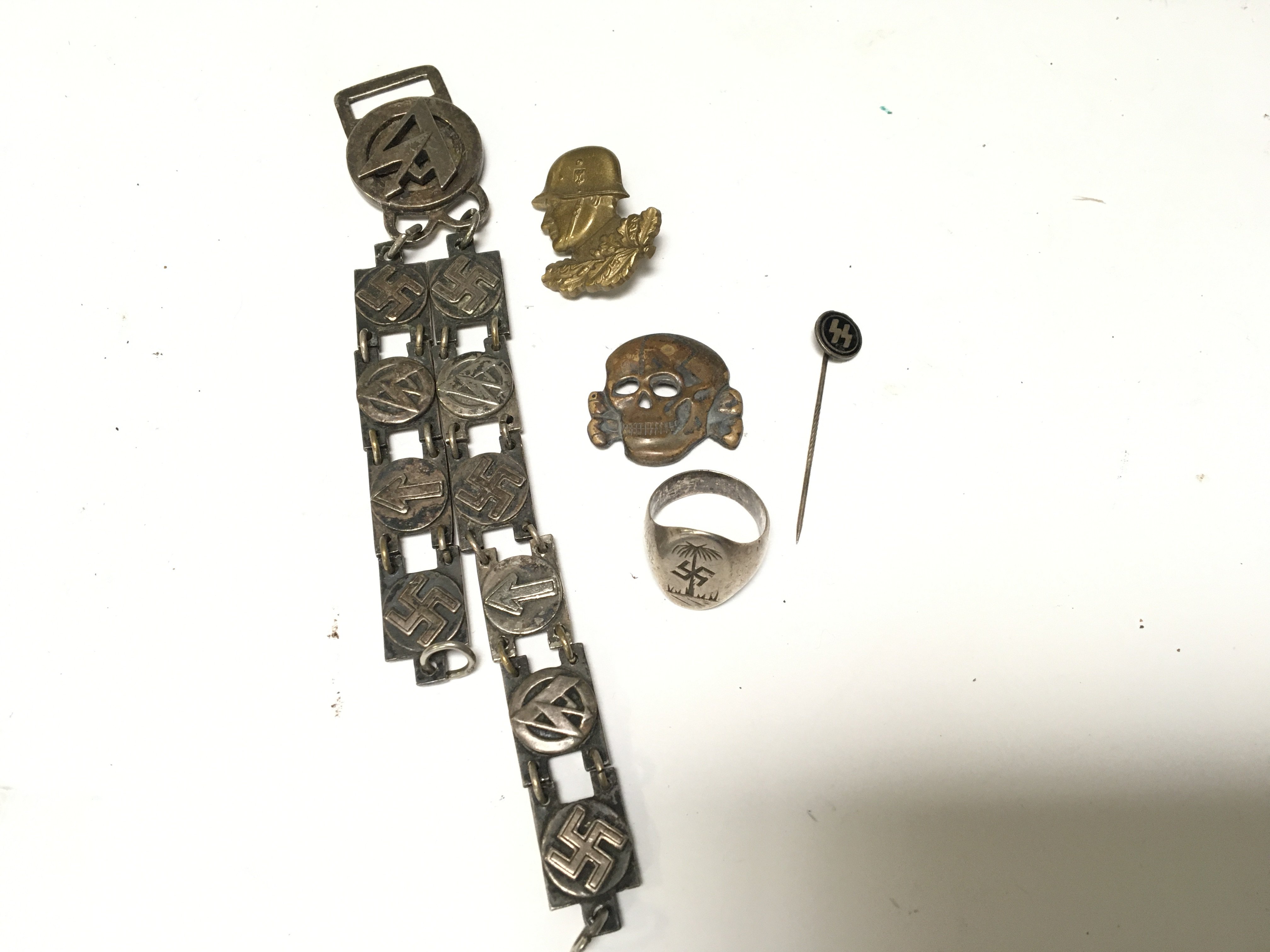 A German Third Reich Afrika Korps silver ring badges a stick pin and a presentation dagger hanger.