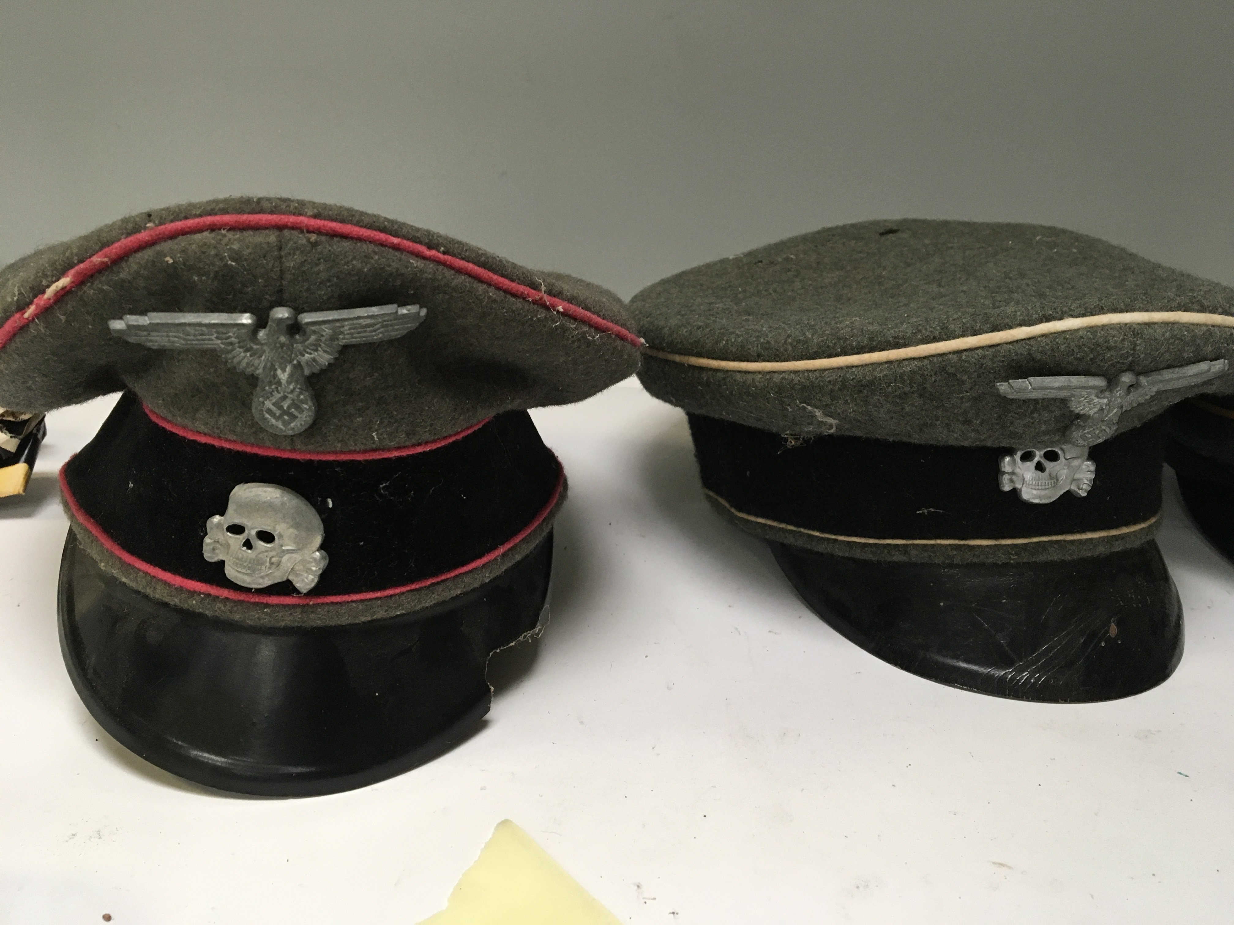 A German Third Reich officers Waffen SS panzer hat with rose pink piping damaged vizier one other SS officers hat and a German Luftwaffe officers hat these appear to be genuine but show signs of wear (3)