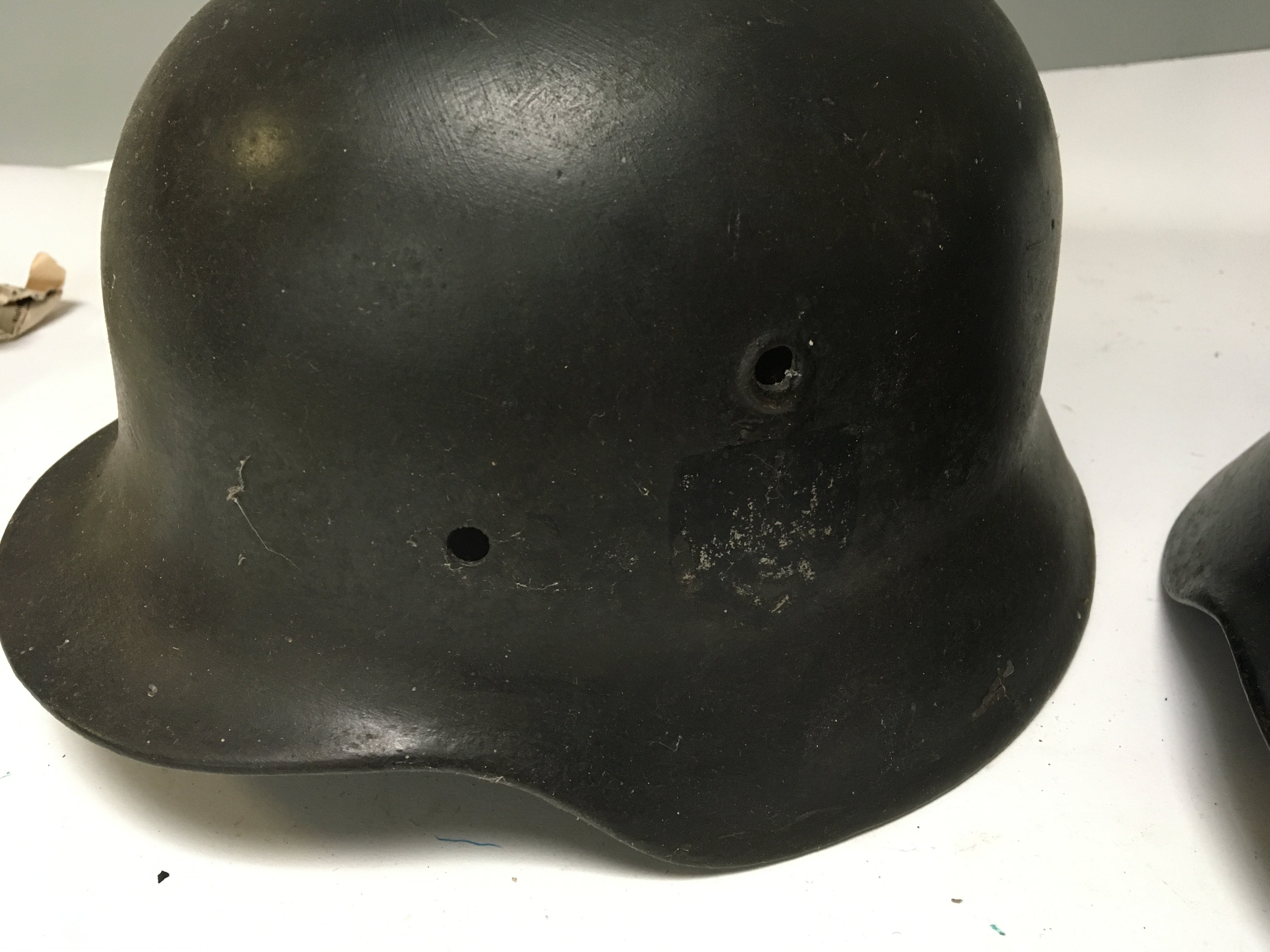 A Genuine German Third Reich M42 steel combat helmet possible SS the side with a faded decal no liner and one other Luftshutz Mk 1 helmet with liner folded edge stamp mark 20490 and painted owner soldiers name. (2)