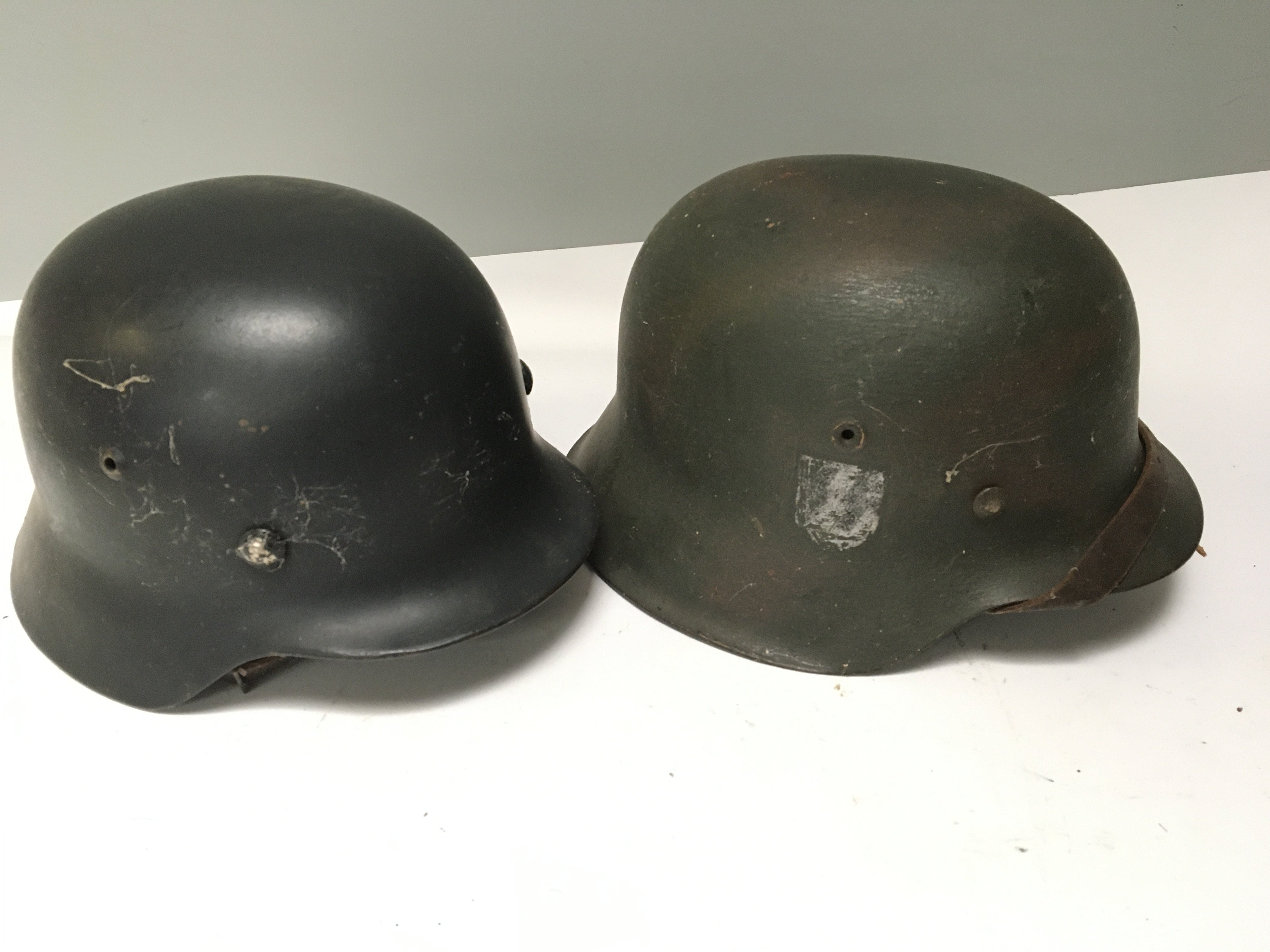 A German Third Reich helmet M42 pattern the side with faded SS decal and one other steel combat helmet possible Spanish both with liners and with soldiers personnel name inscription (2)