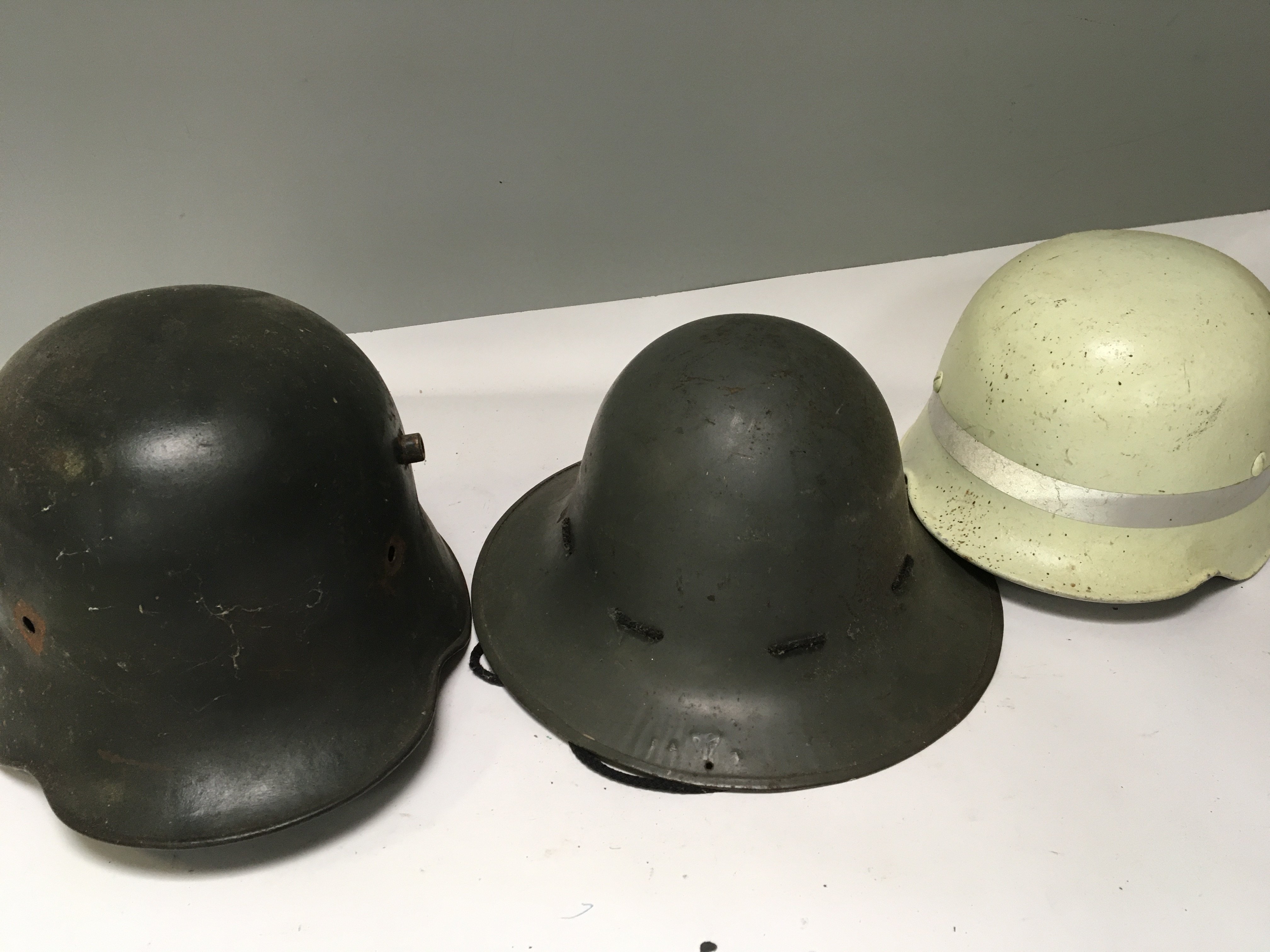 A German imperial I world war steel combat helmet one other helmet and a post war German issue helmet white with a high visual reflective band (3)