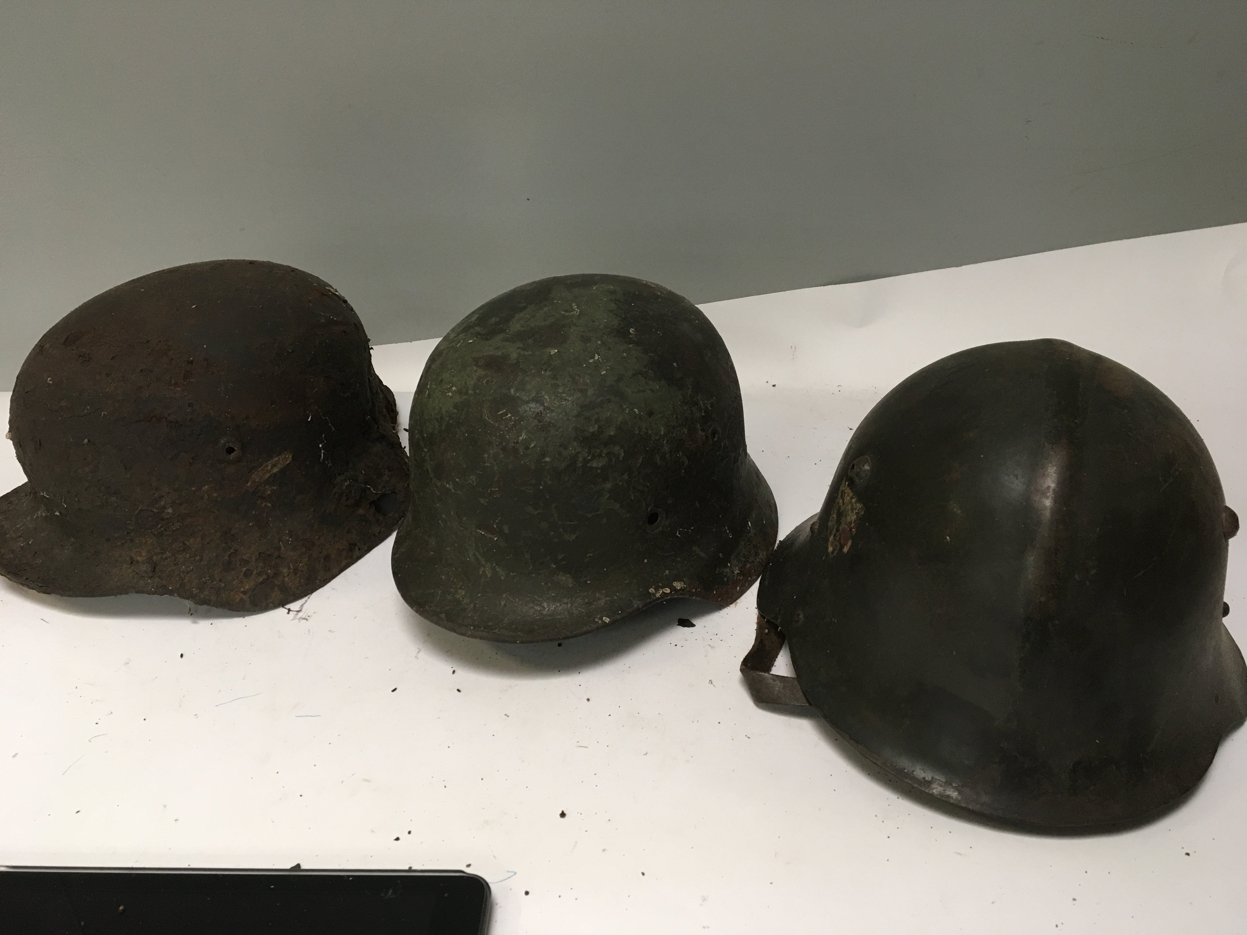 An interesting German steel combat helmet with worn single side decal and a ribbed top original leather lined and a rediscovered dig find Luftwaffe helmet distressed battle condition and one other M42 helmet (3)
