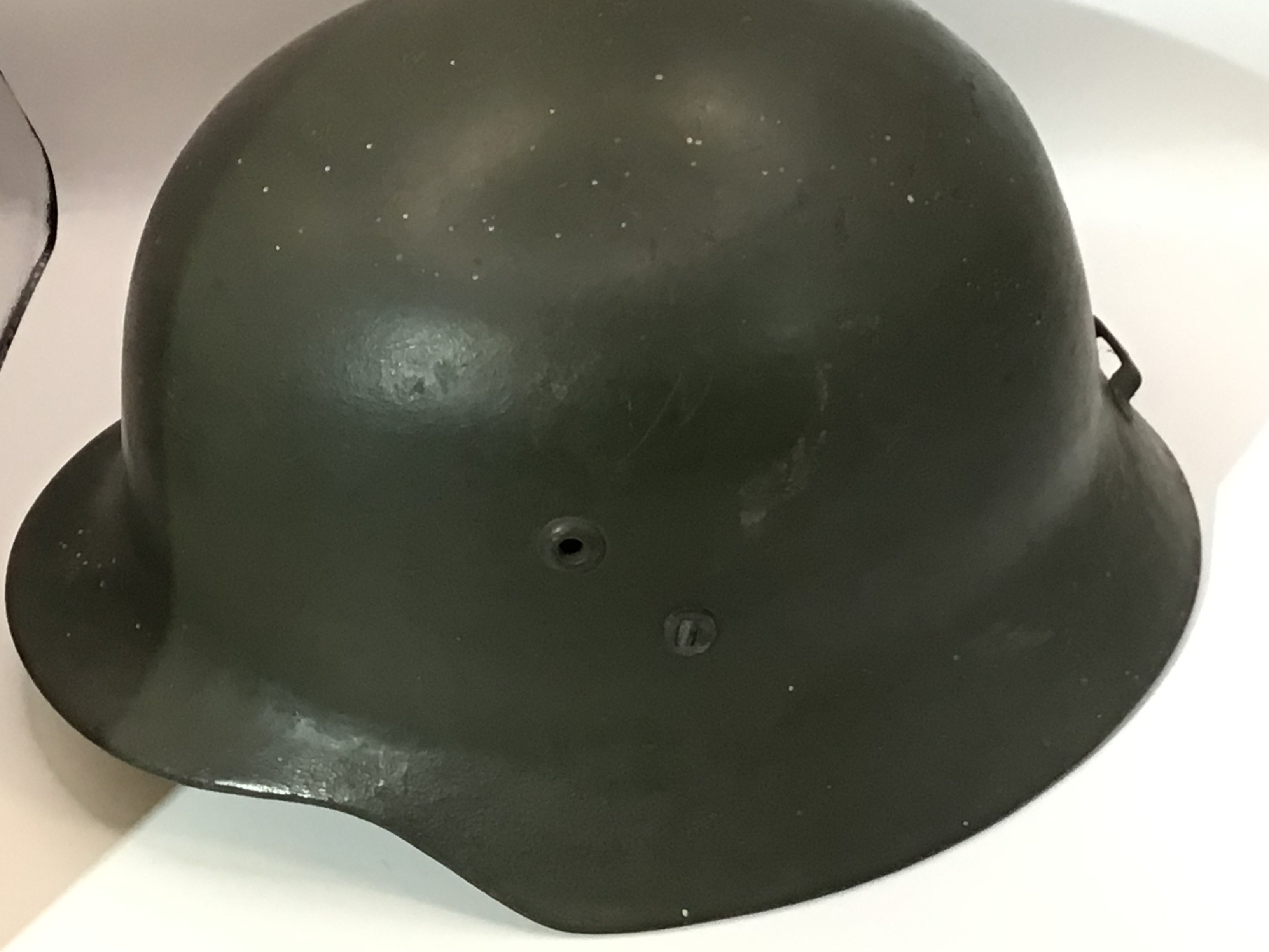 A German Third Reich steel helmet appearing to be original green paint no decal the back edge with an Applied original fitting and with liner no inner edge stamp marks.