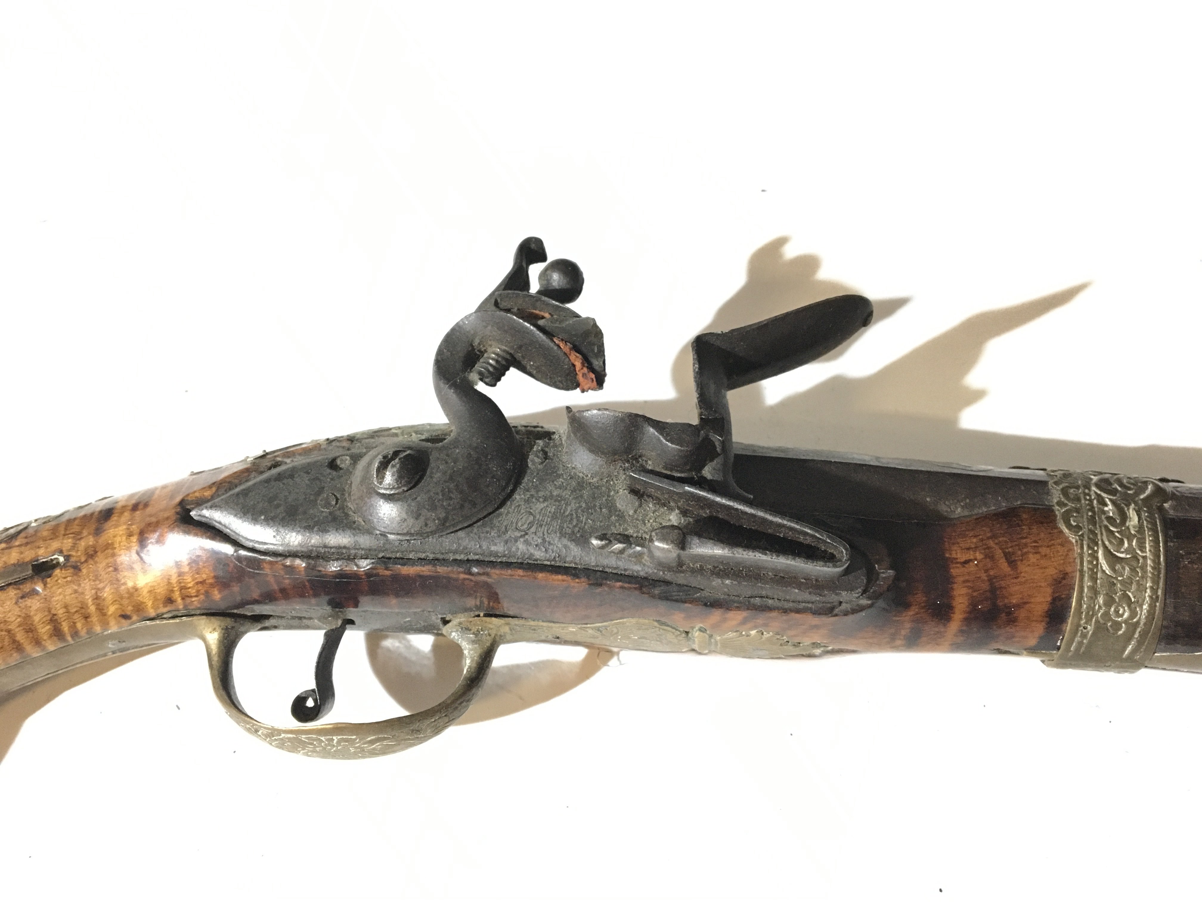 A late 18th Century Spanish flint lock pistol with a figured walnut stock with applied silver and brass ornamentation and patterned barrel action functional.