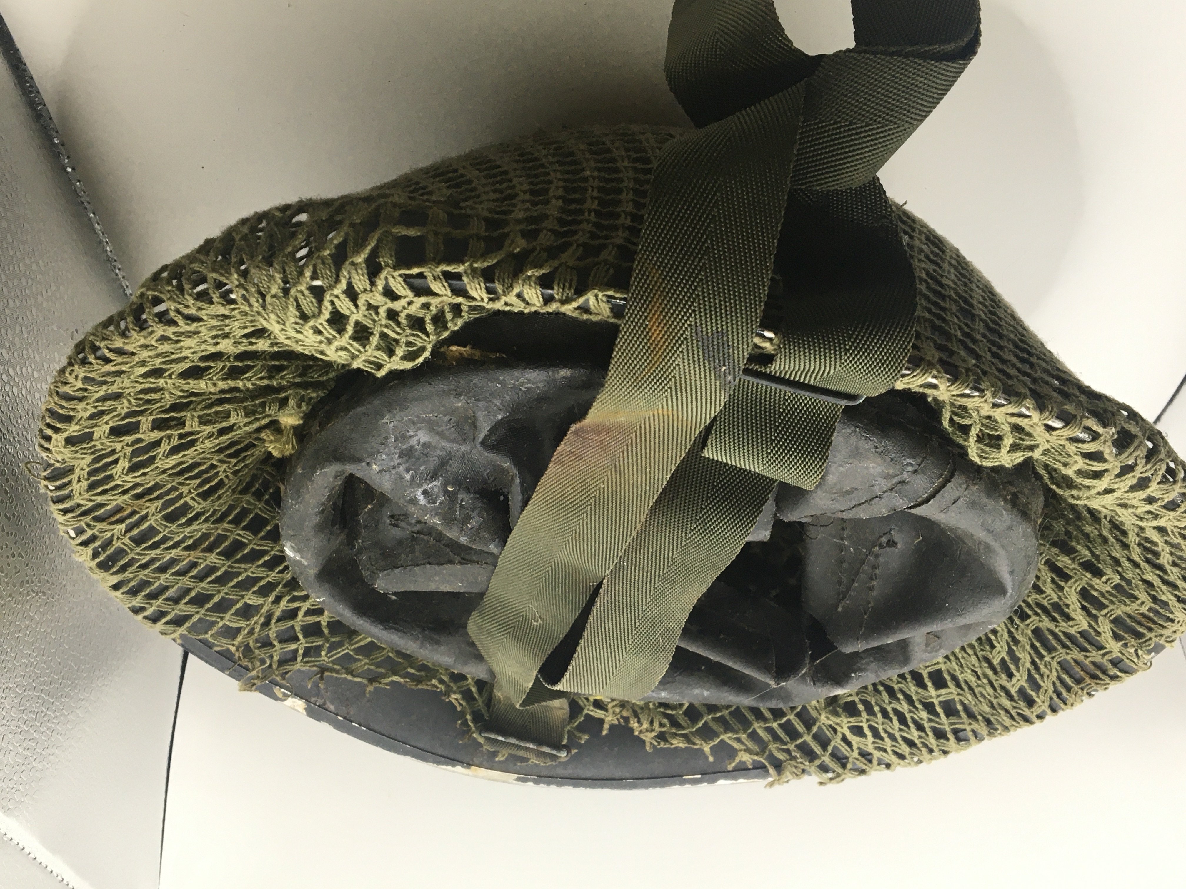 A British Military post Second World War helmet with netting cover and fitted with interior helmet lining. NO RESERVE