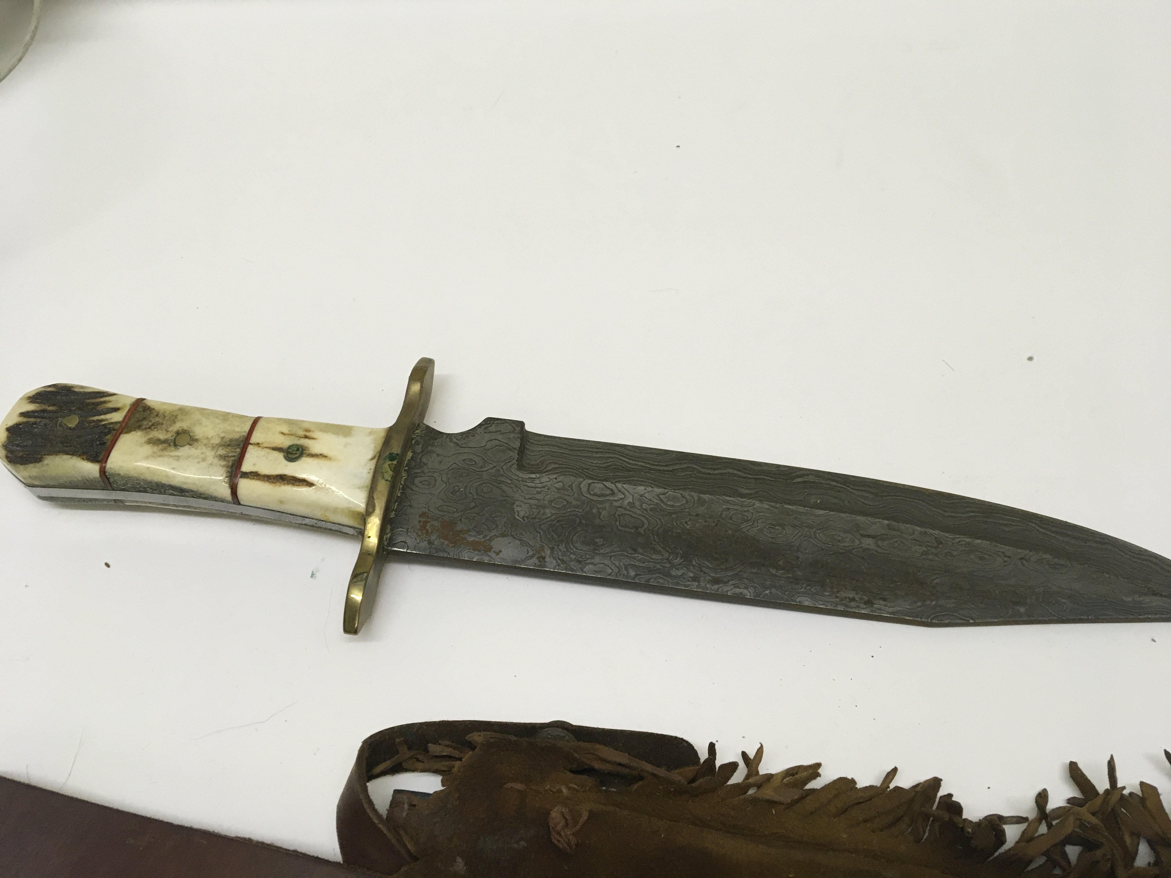 A Native American Bowie Knife with a horn handle and Damascus blade with a traditional North American Indian suede leather scabbard. Length. 43cm