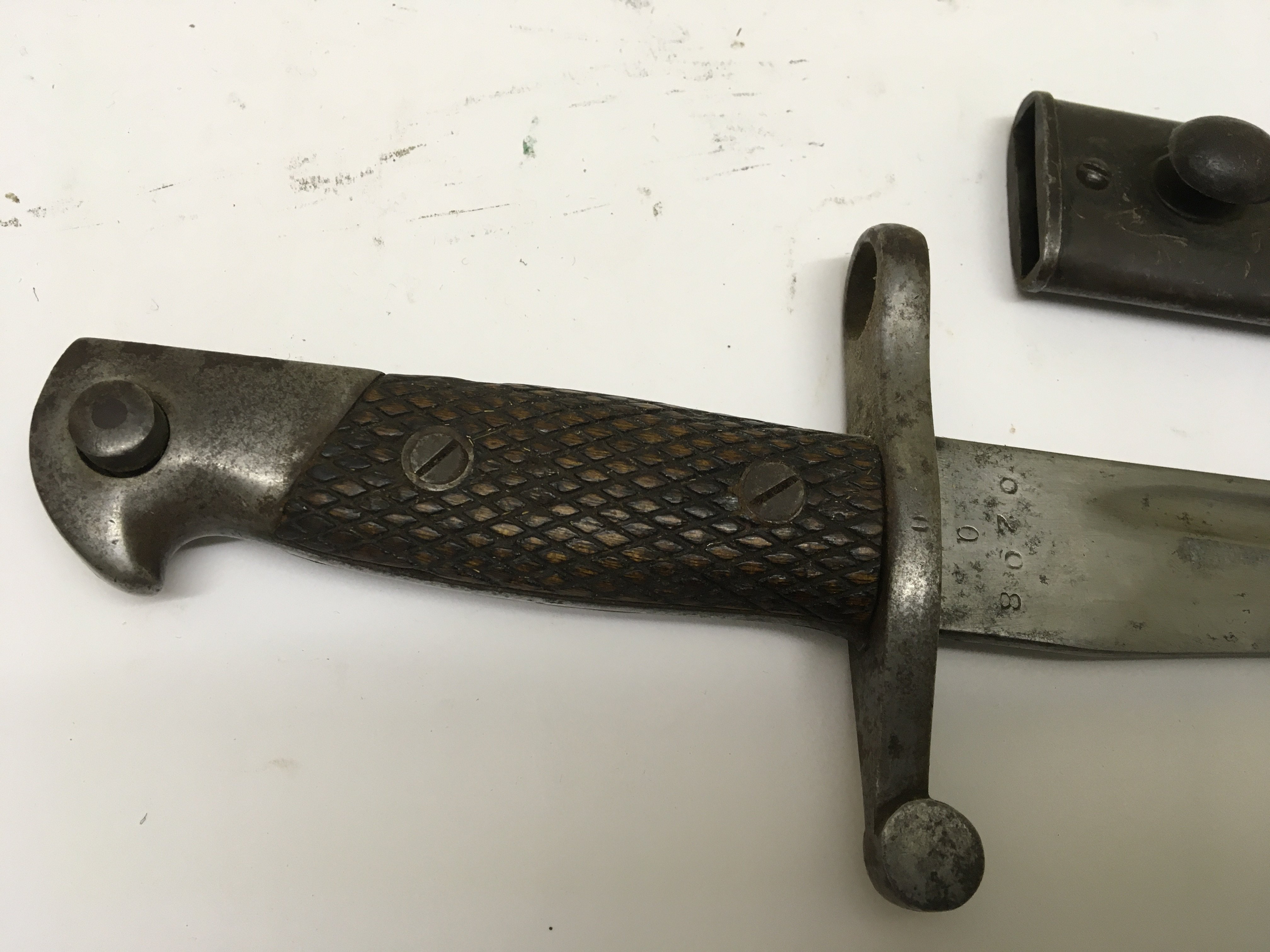 A German Bayonet possible an 1894/89 pattern with wood grip steel cross guard and shaped edge blade metal scabbard.