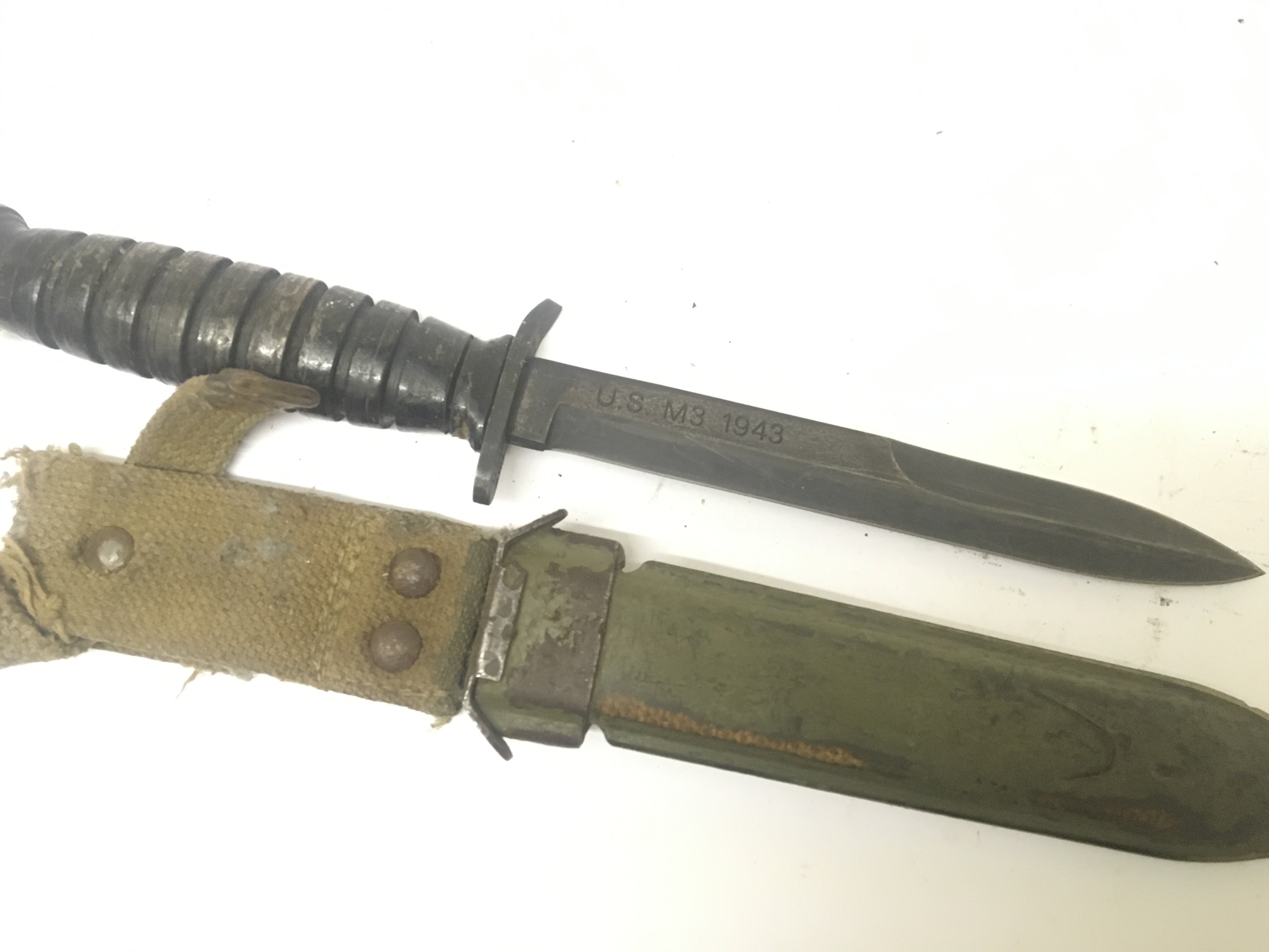 A US II world war fighting knife the blade stamped US M3 1943. Nice original example showing good wear in keeping with war use.with metal scabbard and woven belt frog.
