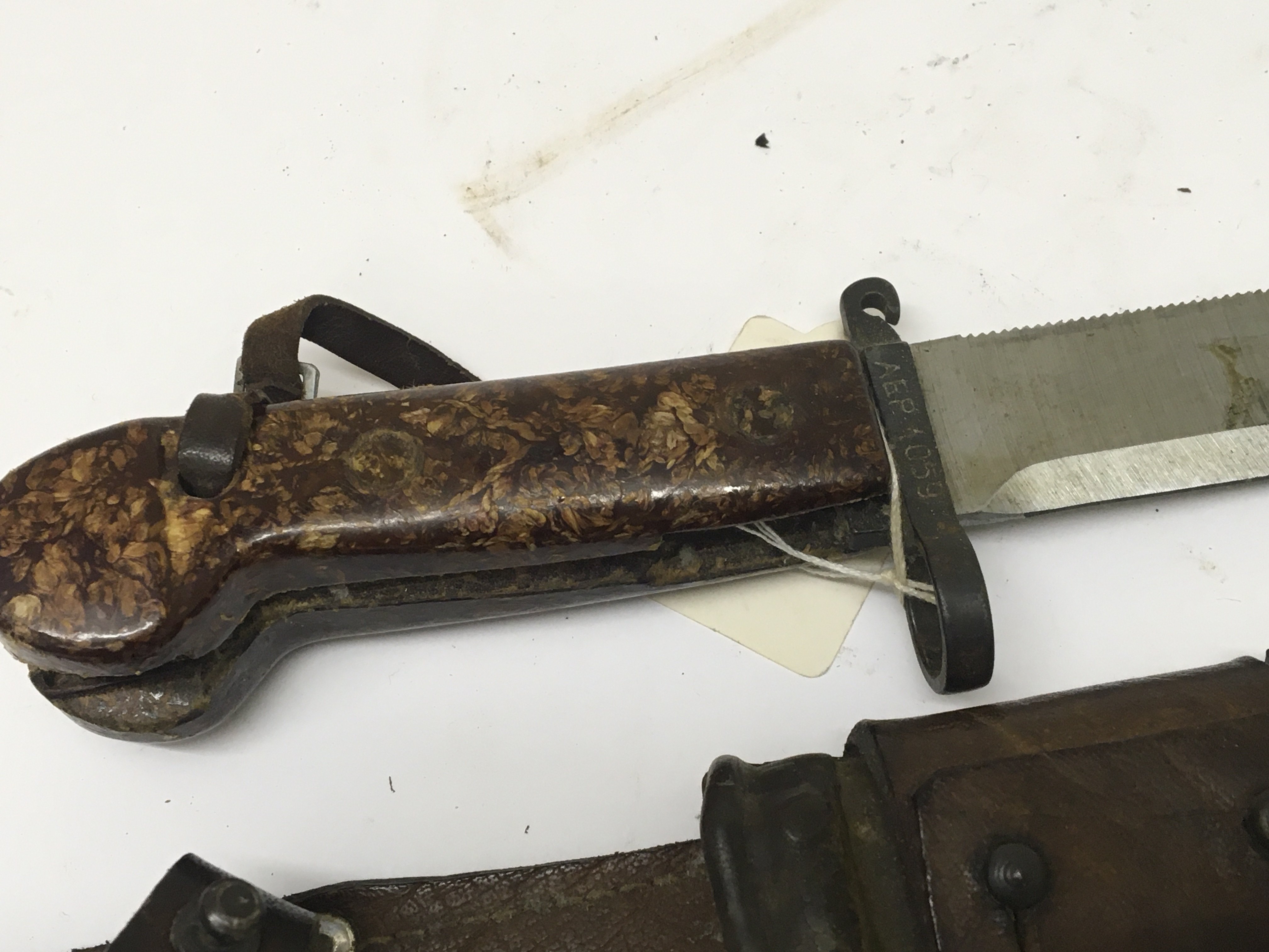 An Early Example of an AK47 bayonet with leather attached frog the cross guard stamped AEP 1059. With Bowie type blade and saw edge. NO RESERVE