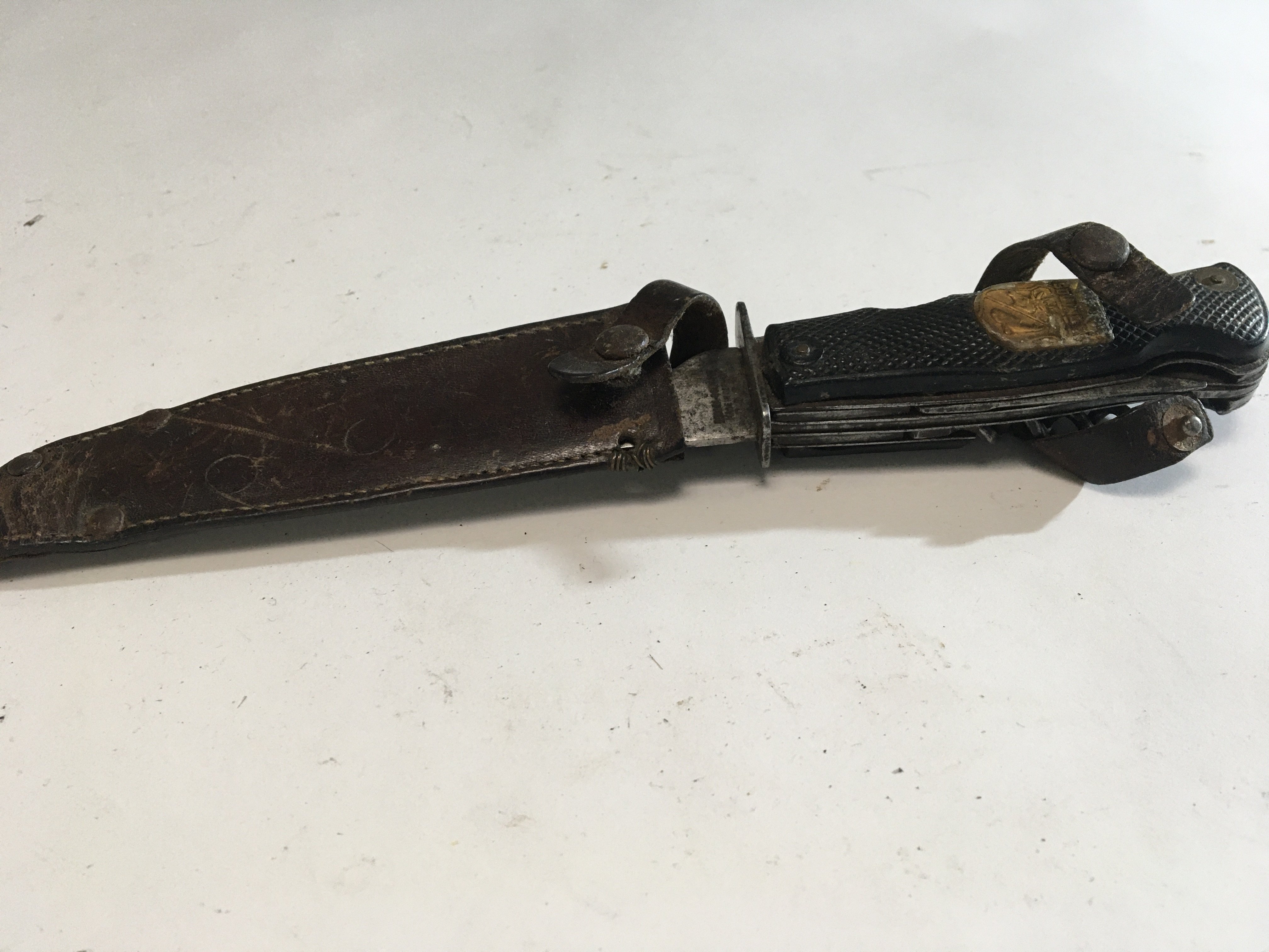 An interesting Vintage German Solingen multi functional knife with steel blade and makers stamp in a leather scabbard.