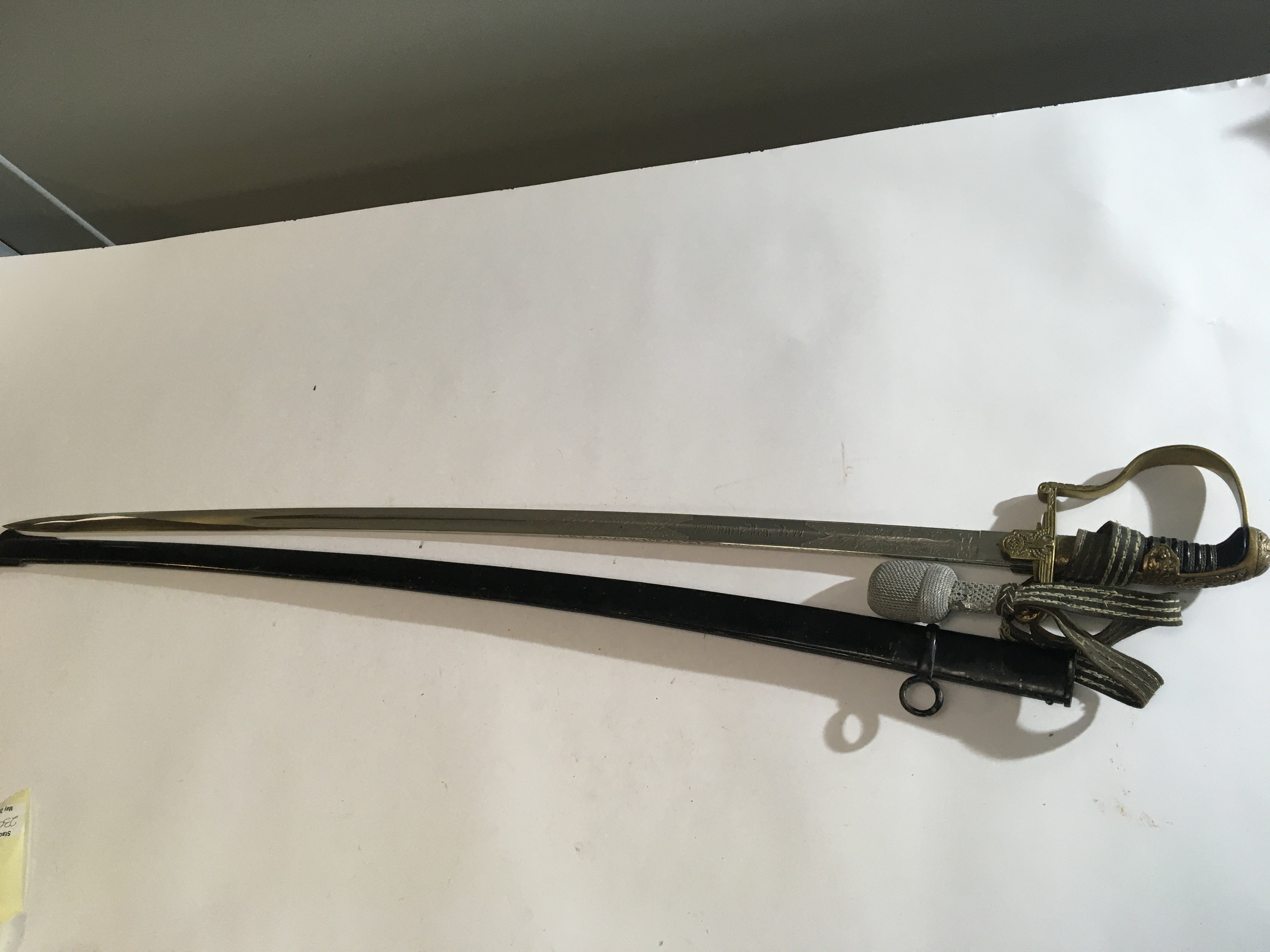 A German Third Reich Military officers dress sword with a brass grip with Swastika and attached pommel the blade with ornate double sided and edge pattern Fullered with slightly curved blade. Good condition.