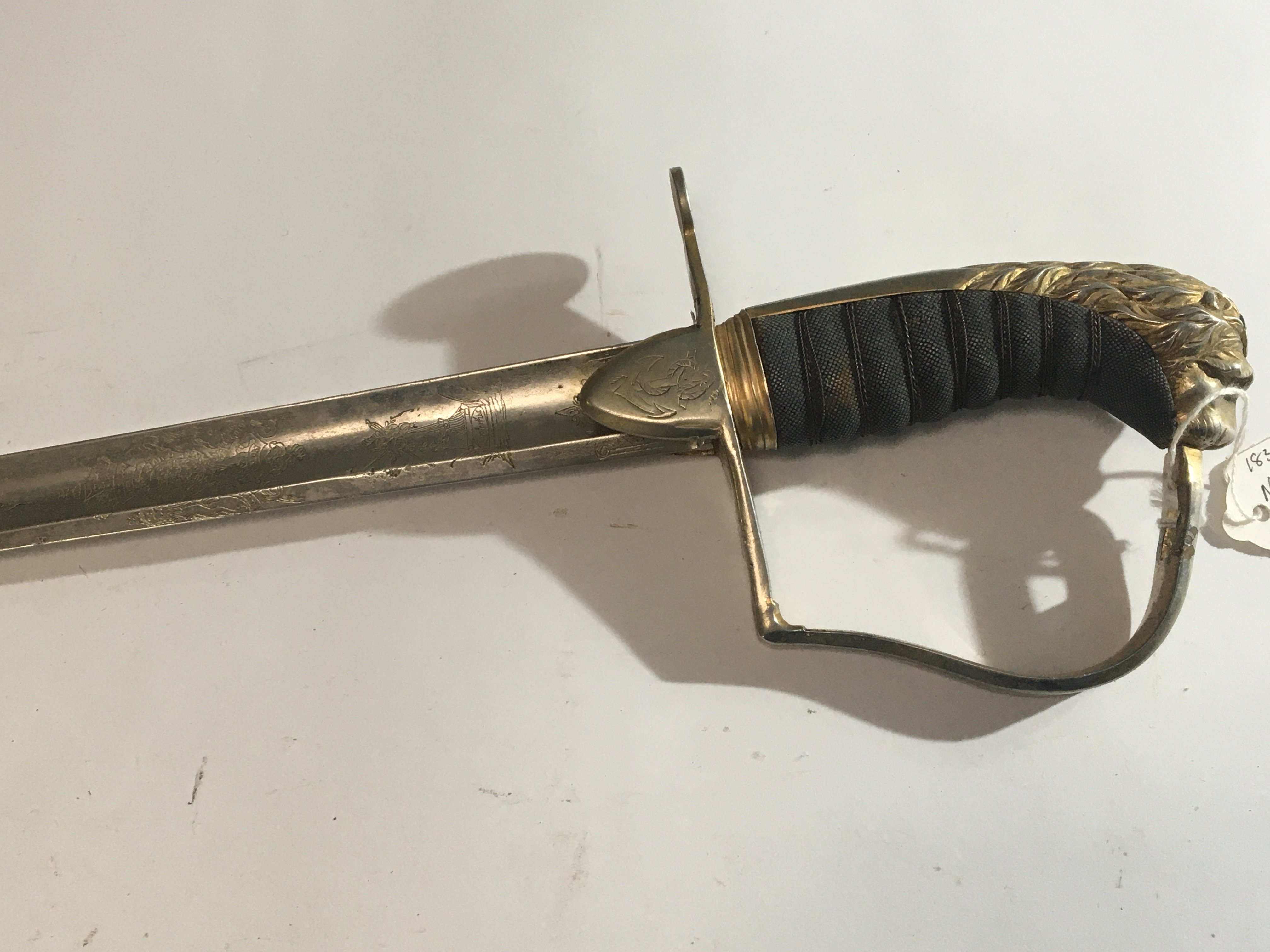 A German Navel officers sword with lion head pommel wired grip the blade with engraving possible an 1830 pattern. No scabbard engraved blade edge