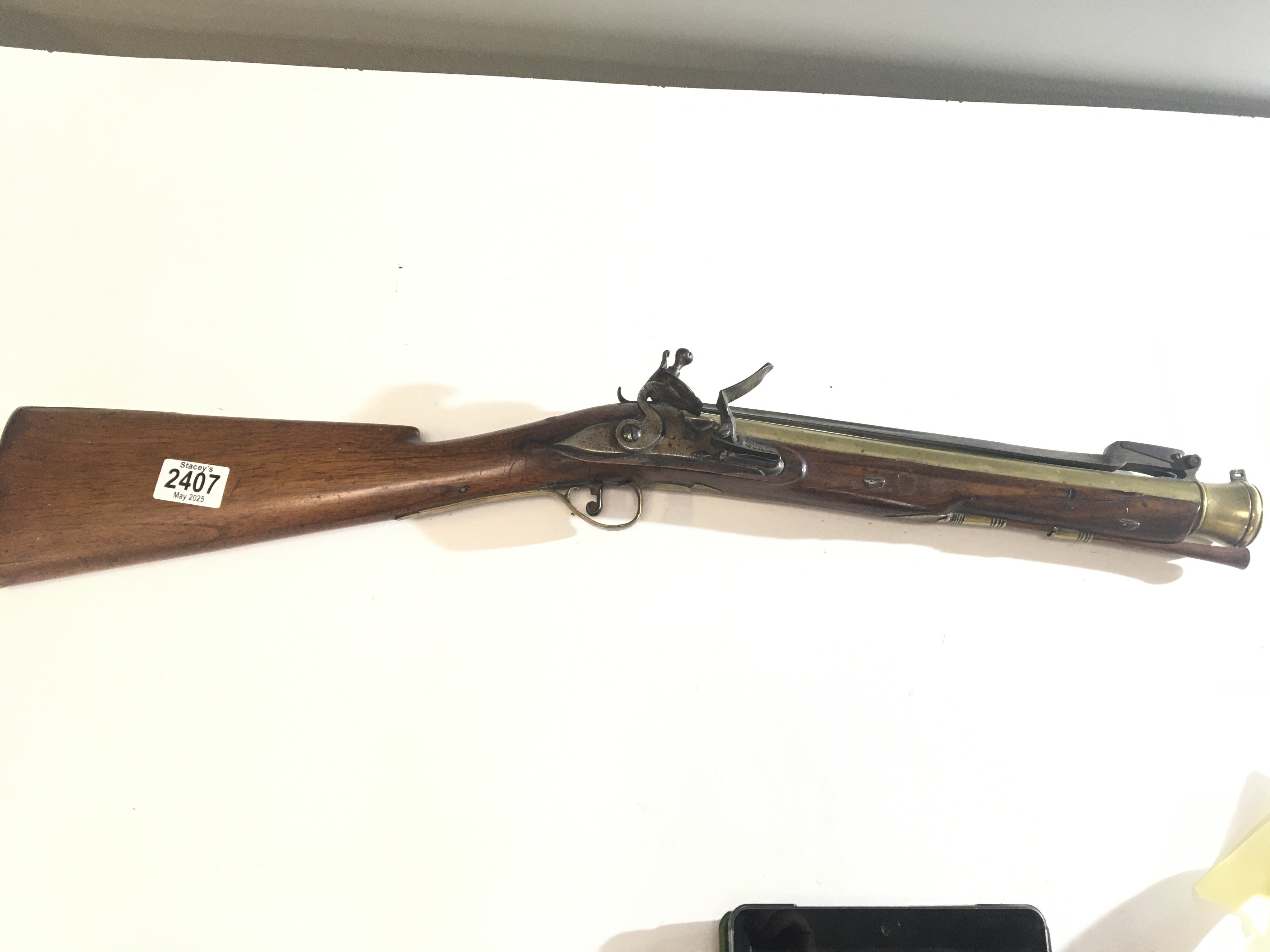 A late 18th century British Blunderbuss with brass canon barrel full length walnut stock brass fittings steel action and with a long flick sprung bayonet the barrel with proof house marks nice condition functional action.
