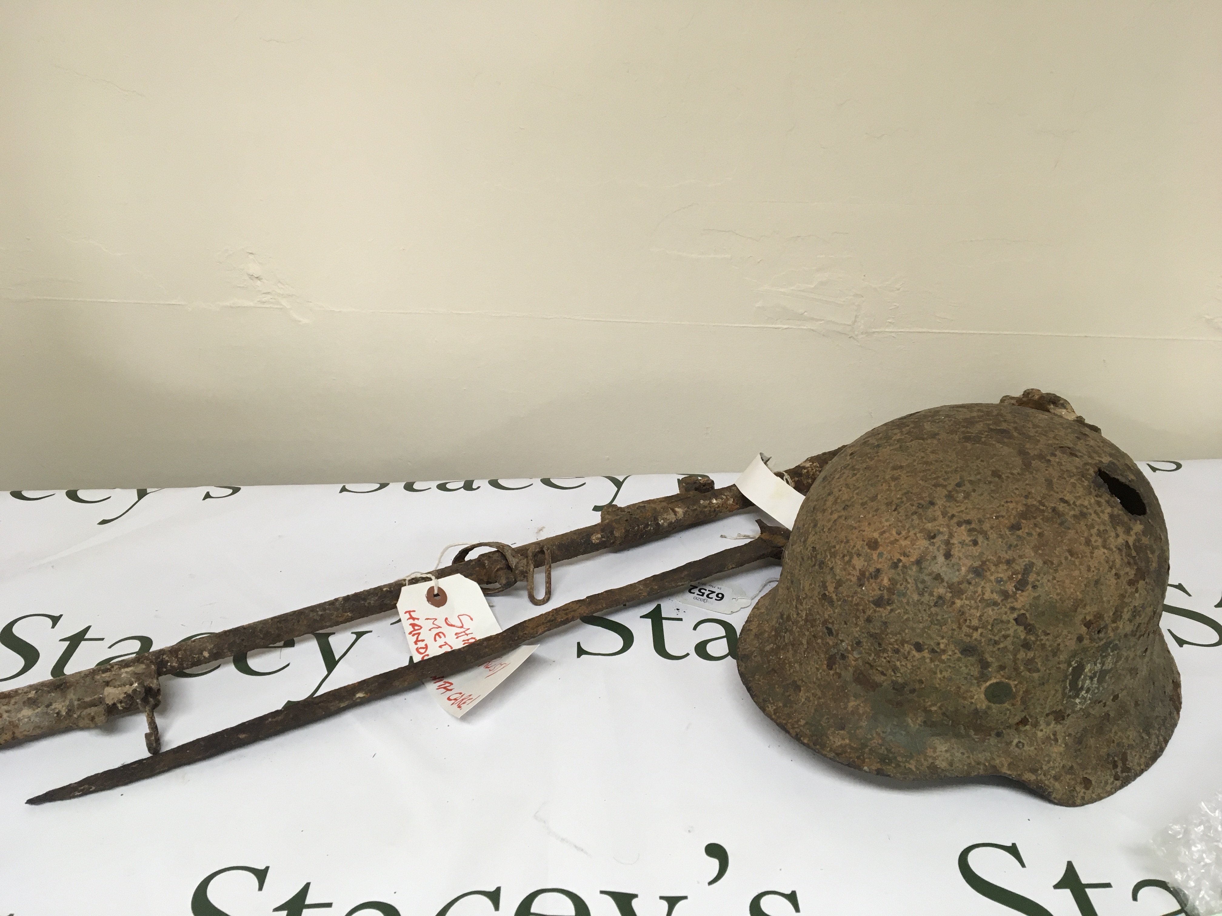 A I world war rediscovered relic retrieved from the ground on the Somme battle field possible an Enfield 303 rifle with bayonet. Also a German II world war Third Reich SS battle helmet with traces of a single decal the helmet with shrapnel damage.