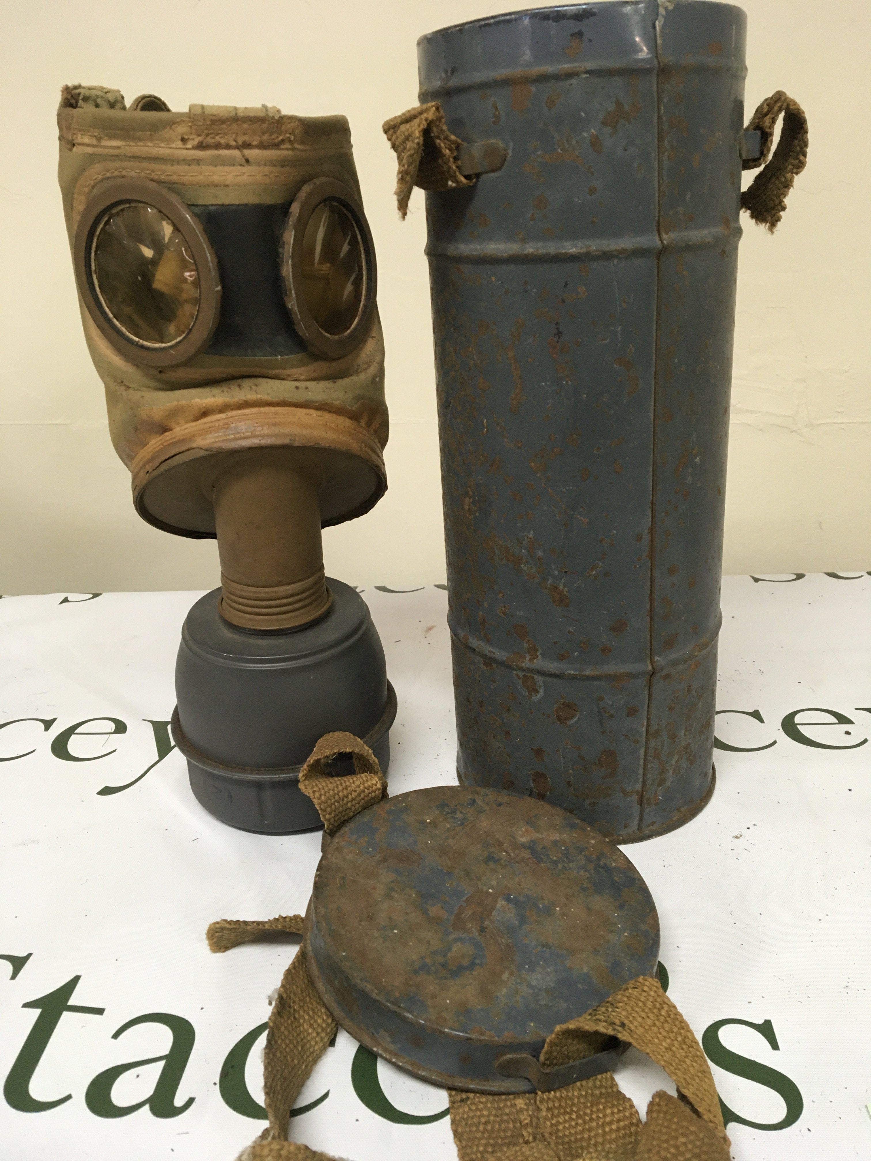 A II world war gas mask within a painted metal canister possible German Third Reich allied forces the base stamped TS-54-39.