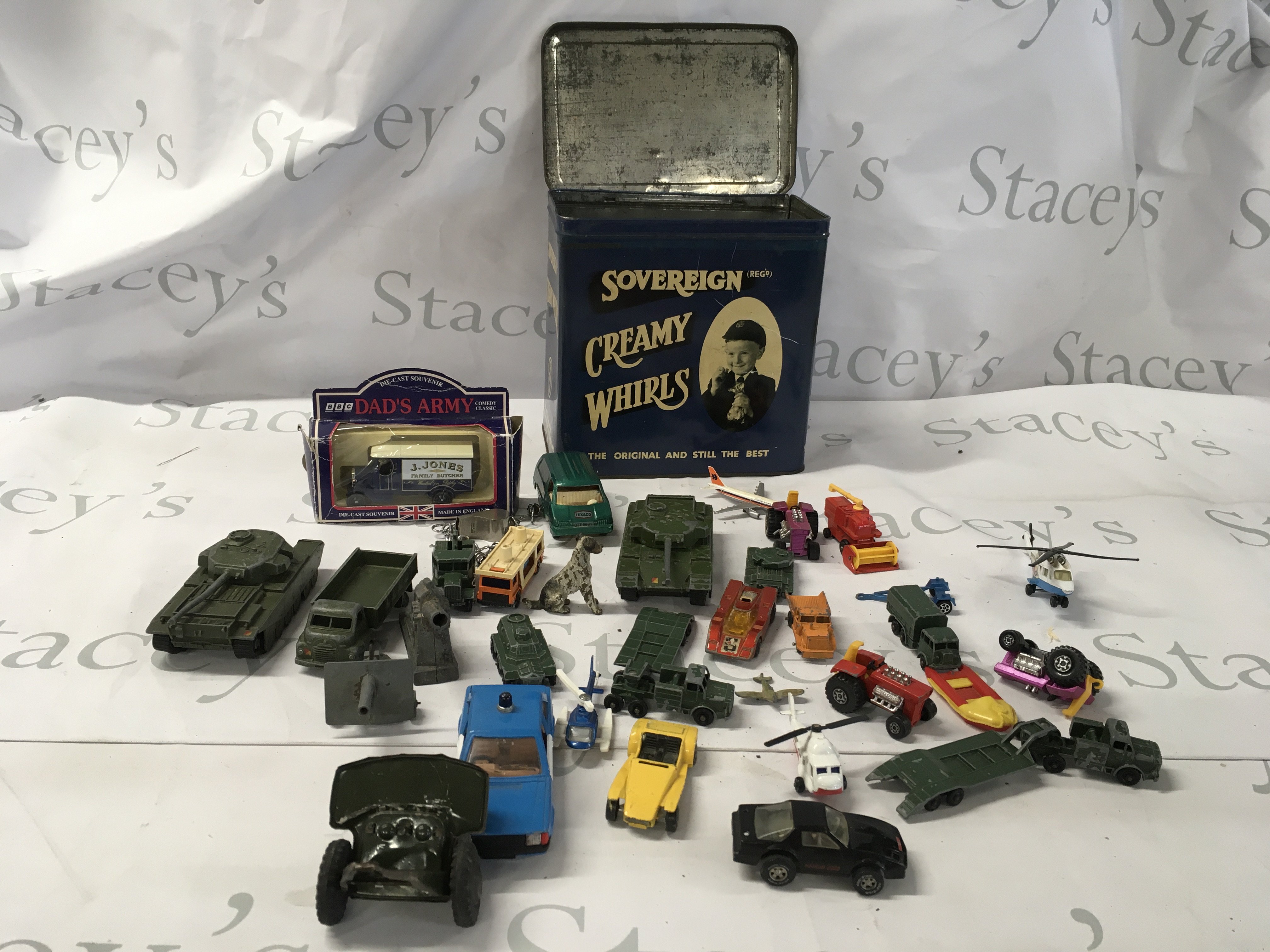 A collection of Playworn diecast and plastic model vehicles including some military items including a vintage tinplate twin barrelled artillery gun made in Japan. The collection comes in an old shop tin advertising Cream Whirls toffees in nice condition. No reserve