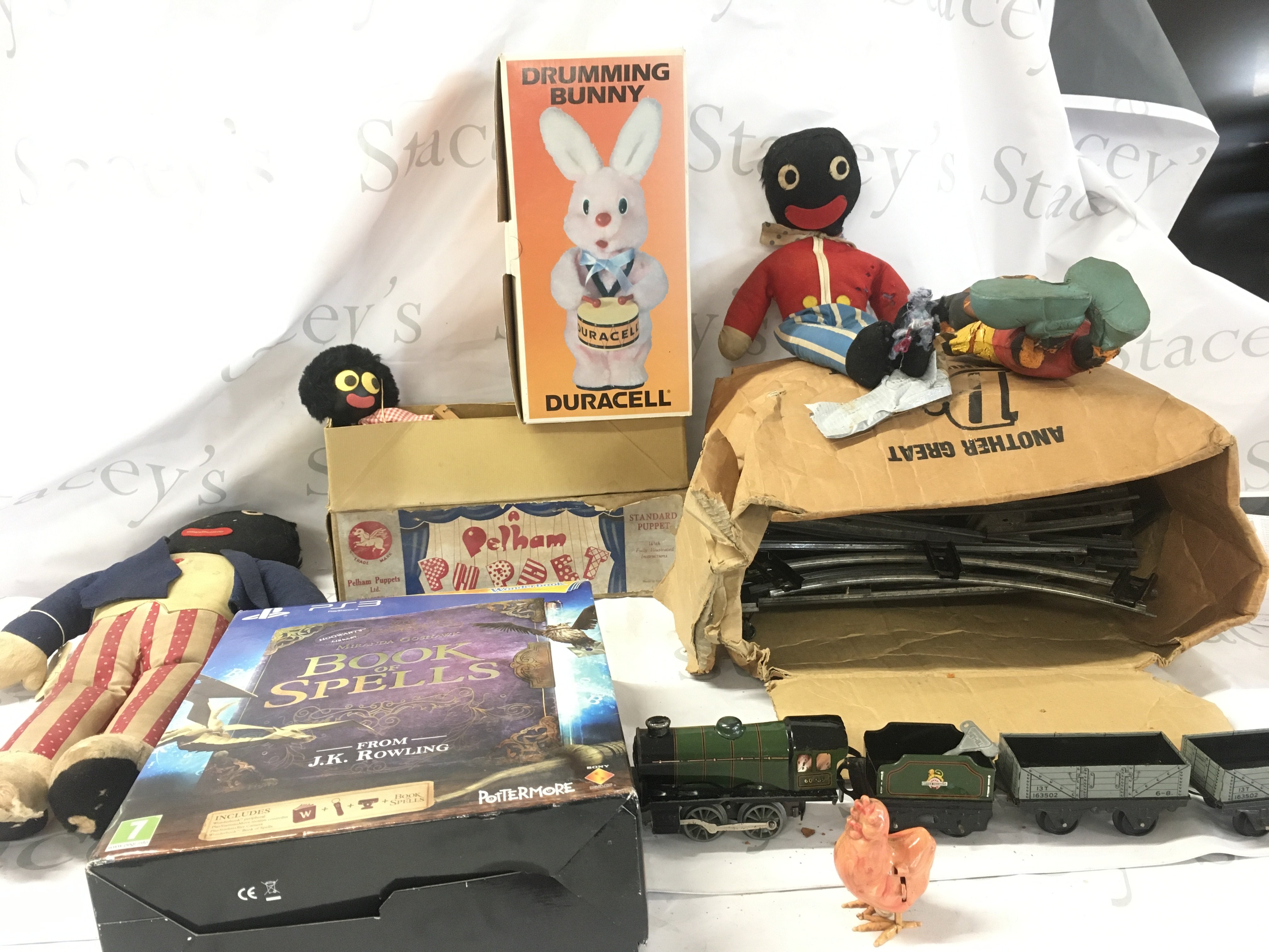 An assorted collection including 3 Gollies one being a Pelham puppet..a boxed Duracell drumming bunny..a Triang clockwork train with track 0 gauge..a perished vintage Mickey Mouse and a PS3 Book of Spells. No reserve