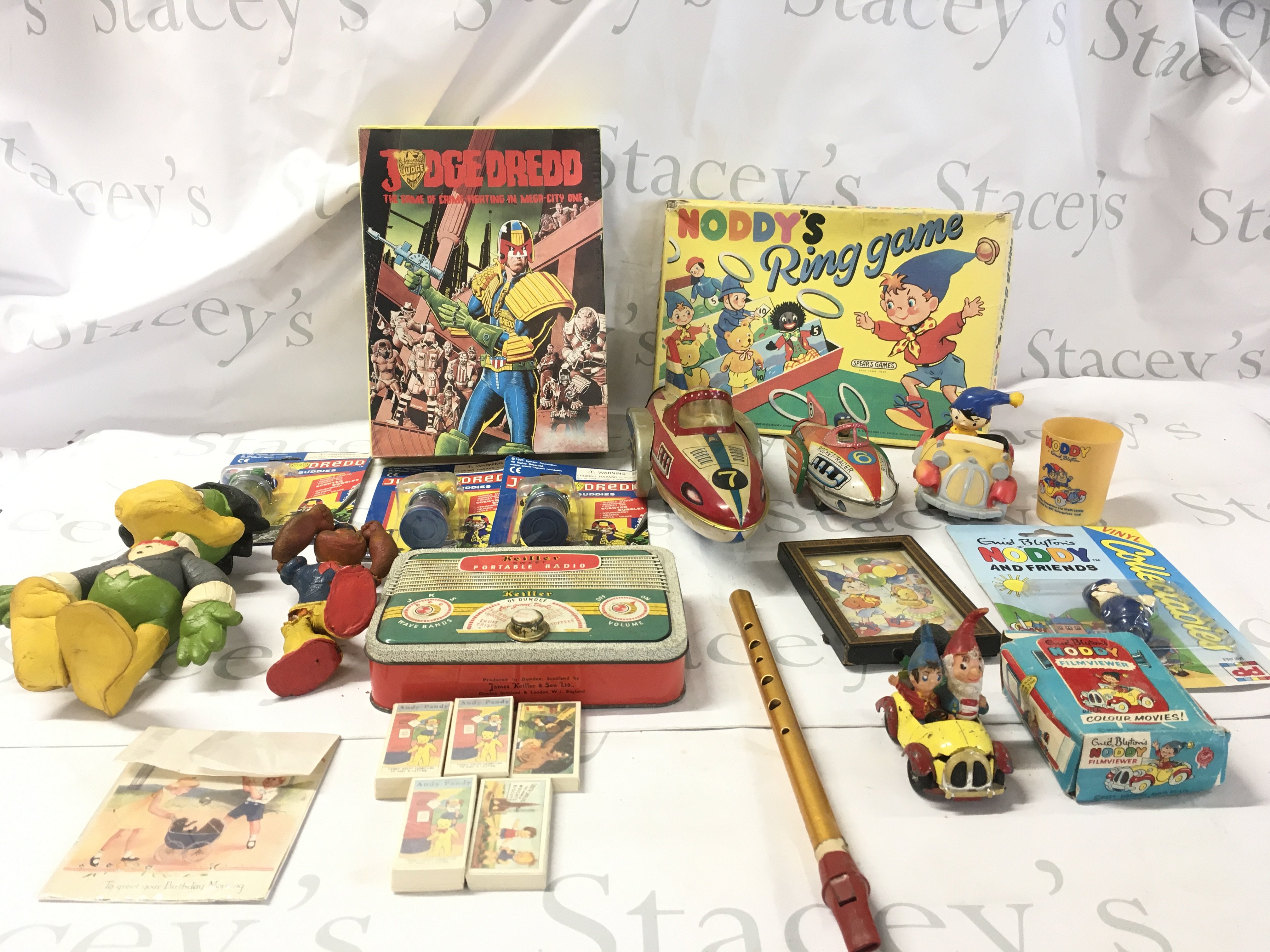 An assorted collection of toys featuring Noddy..Judge Dredd and others. Includes boxed games..bendy toys..tin rocket racers..collector cards etc.. No reserve