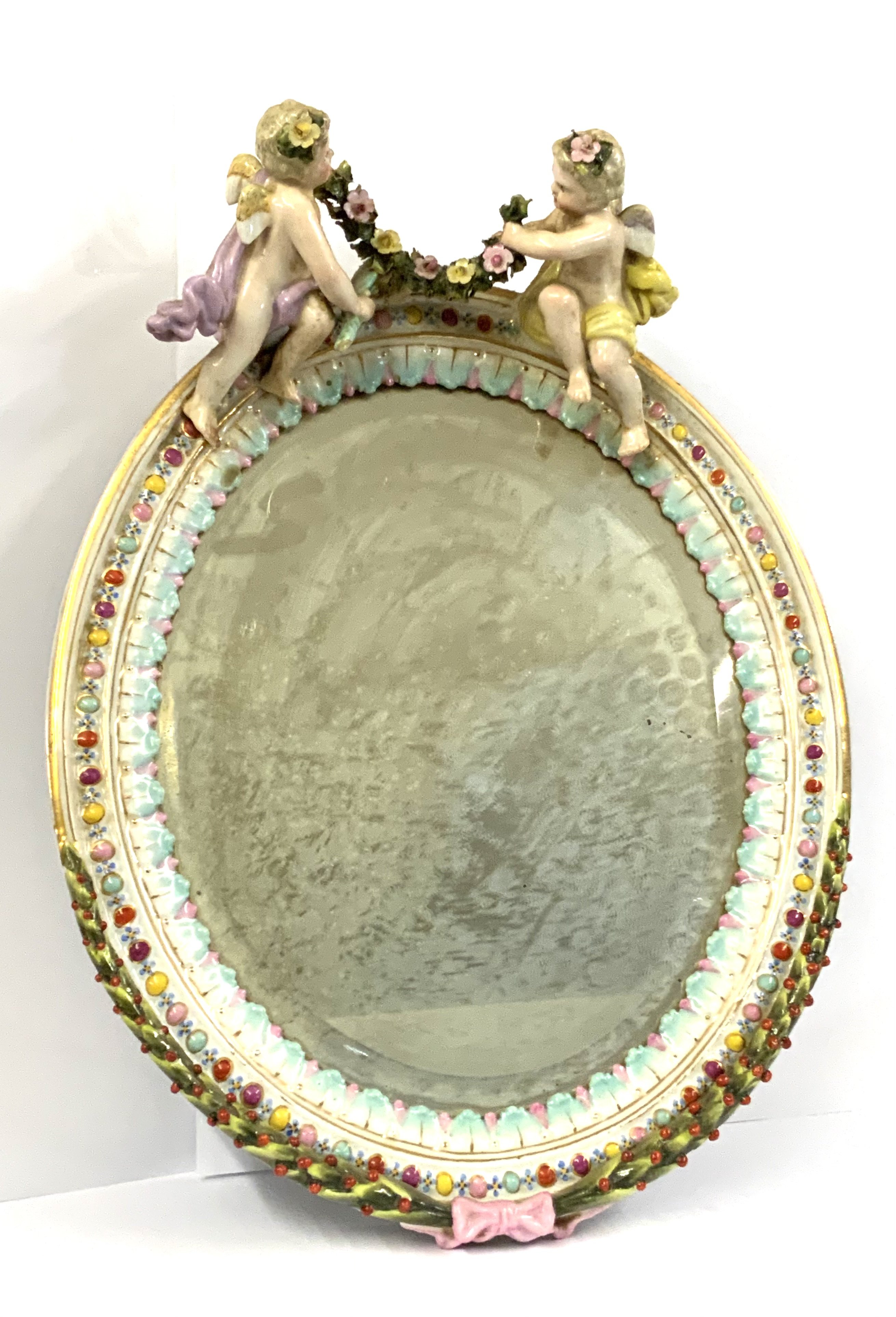 A pair of German porcelain cherub wall mirrors. 34cm x 25.5cm