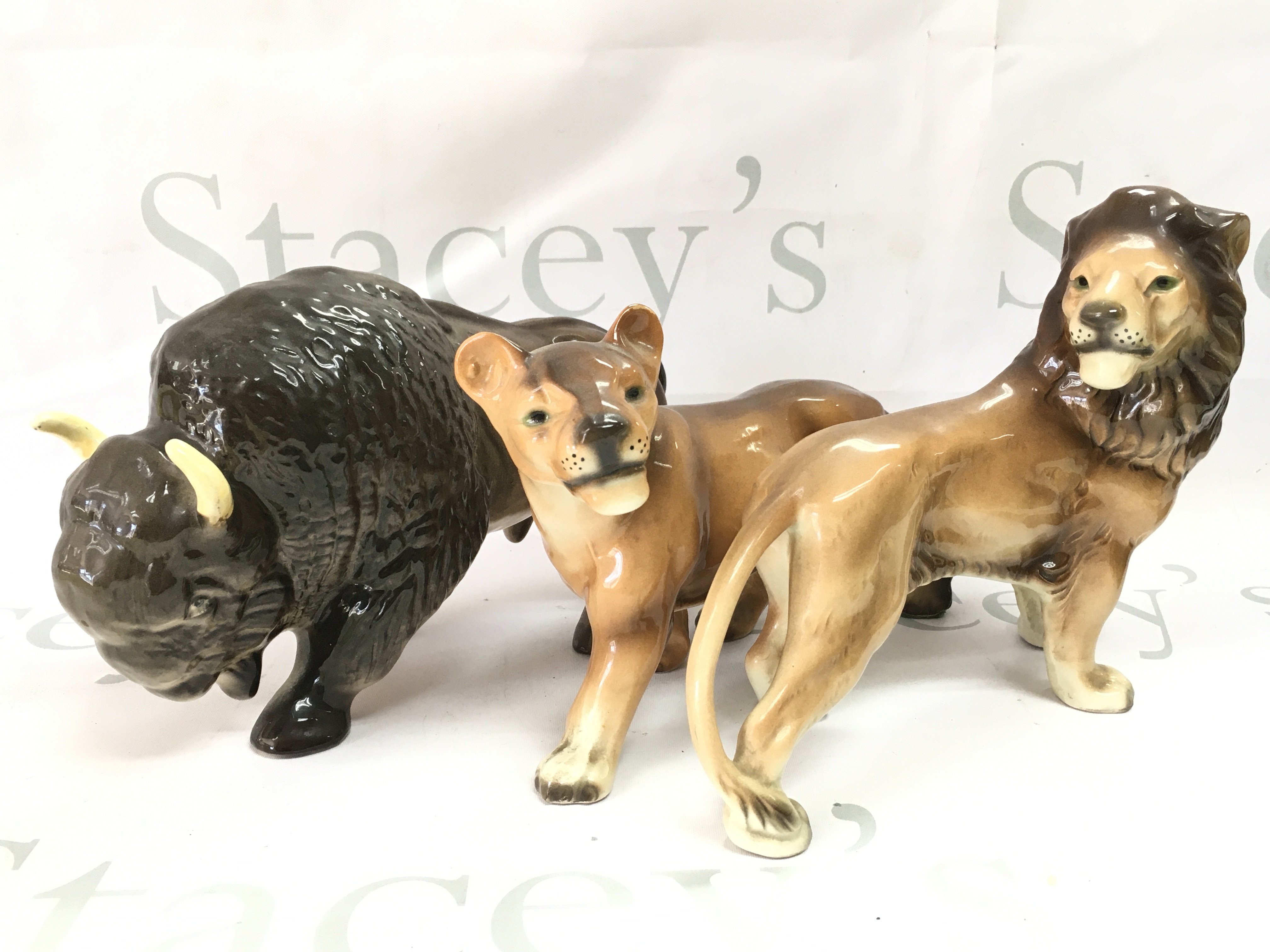 Three ceramic animals including West German Made lions and a Melba Ware buffalo . This lot cannot be posted