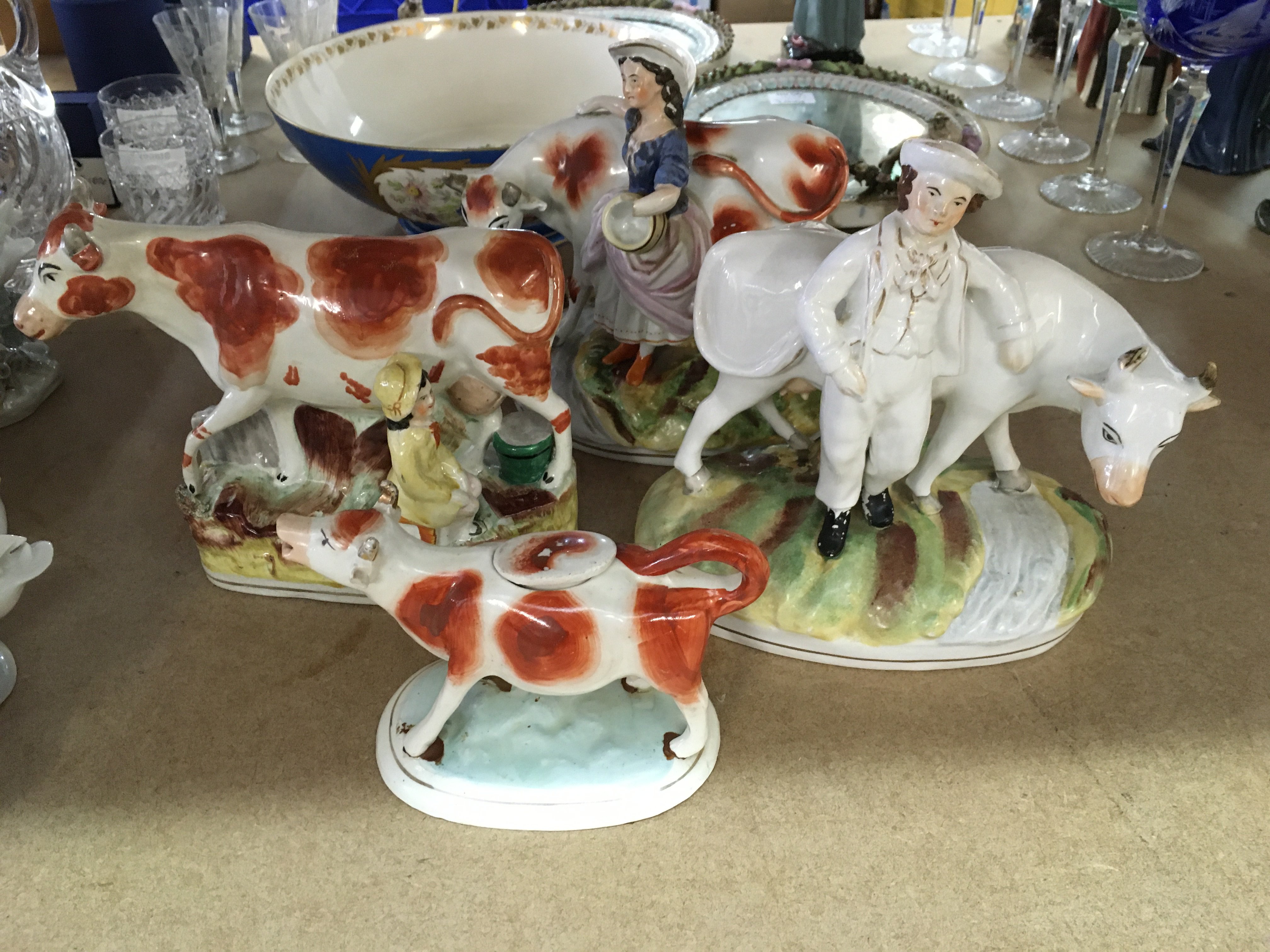 A collection of four Staffordshire figures cows and figures including a creamer .