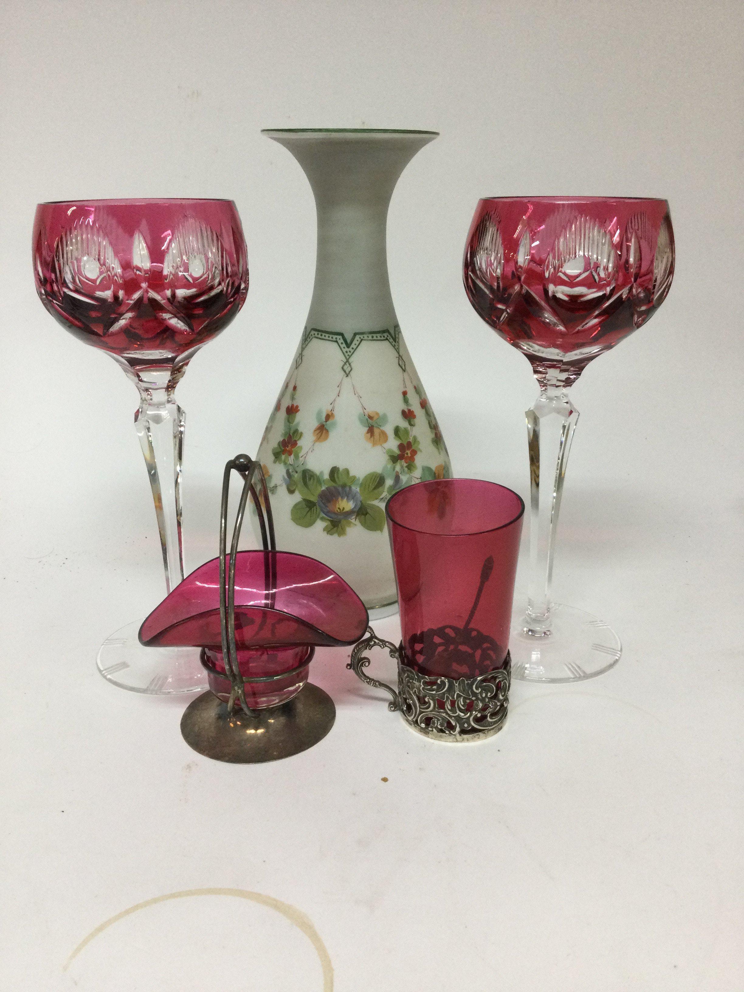 A collection of glass ware including two wine glasses a vase glass beaker with silver rim and a small Cranberry basket .