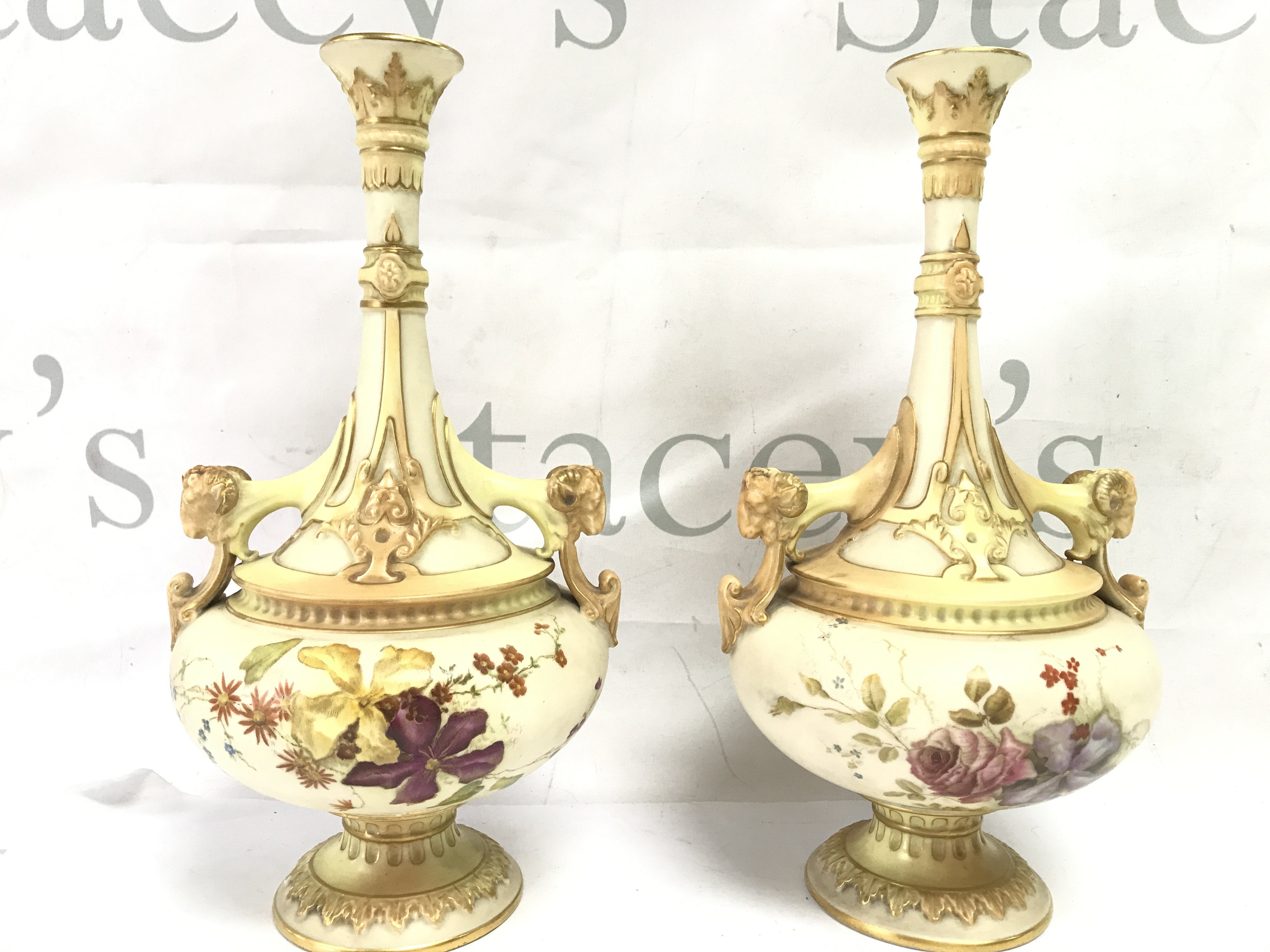 A pair of Royal Worcester vases with floral decoration and goats heads handles and a pair of Worcester shell dishes . This lot cannot be posted