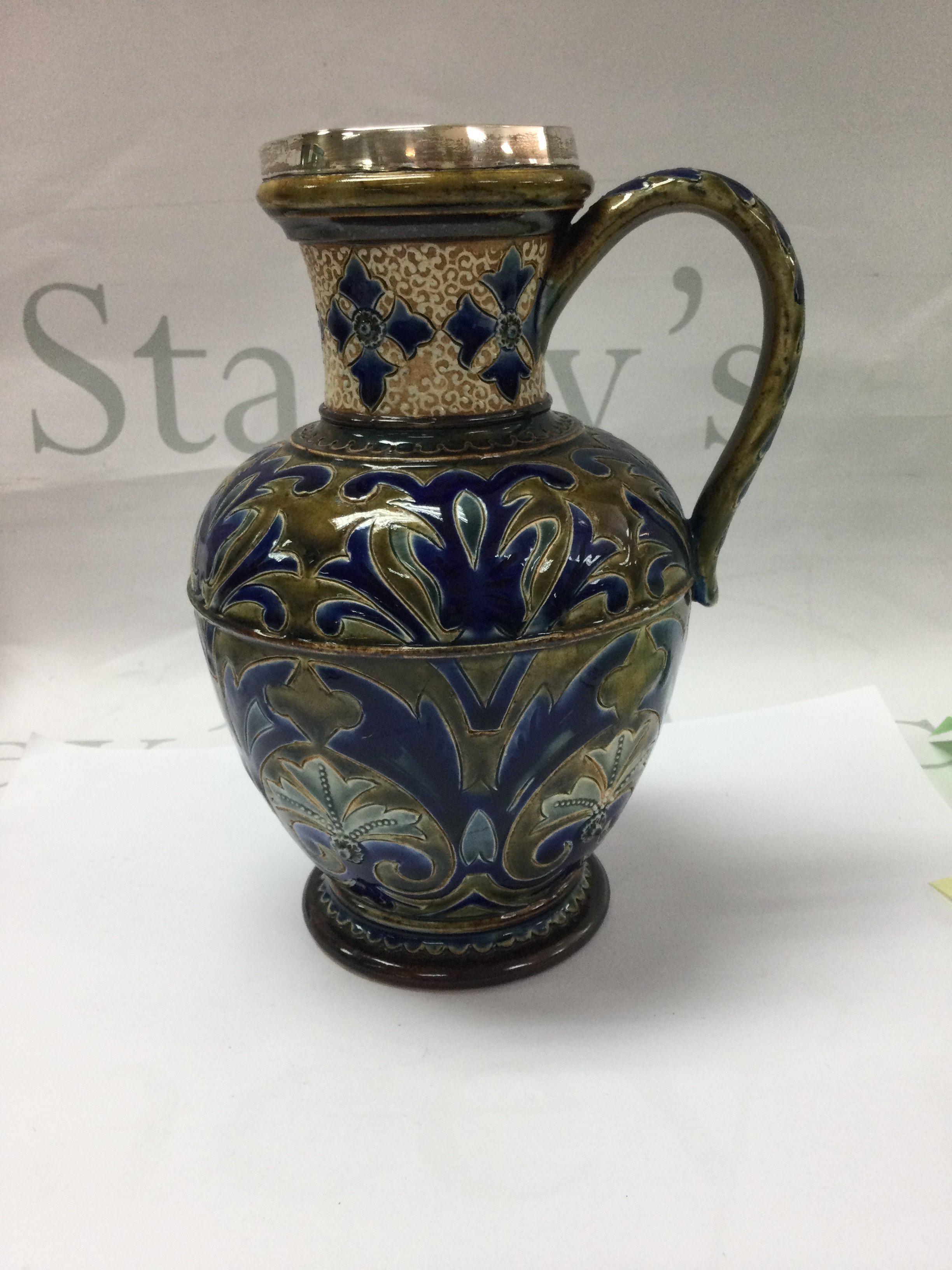 A Victorian Doulton Lambeth jug decorated with floral design with silver Plated rim 20 cm .