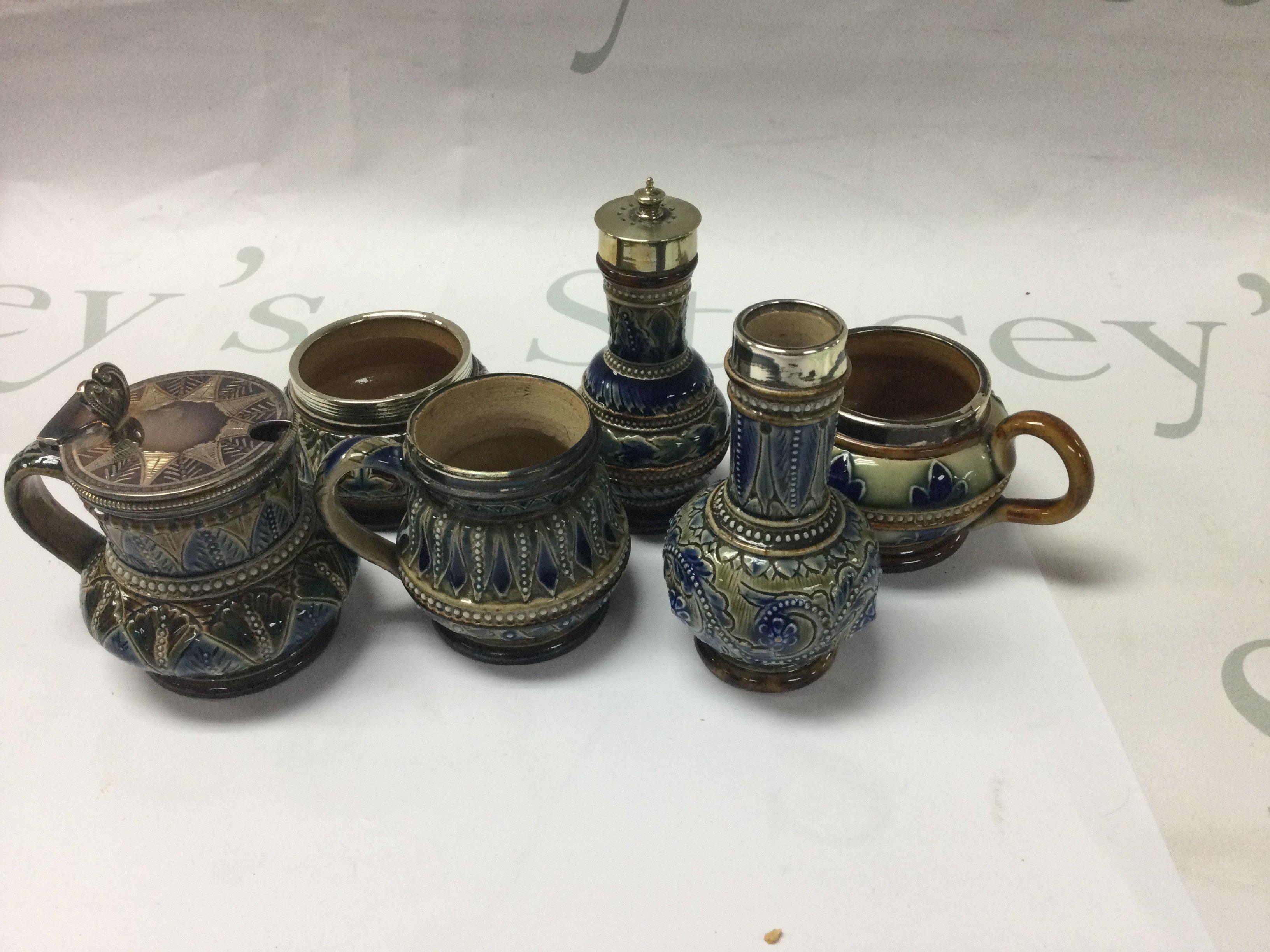 A collection of six Doulton Lambeth cruets with silver plated mounts And floral decoration .