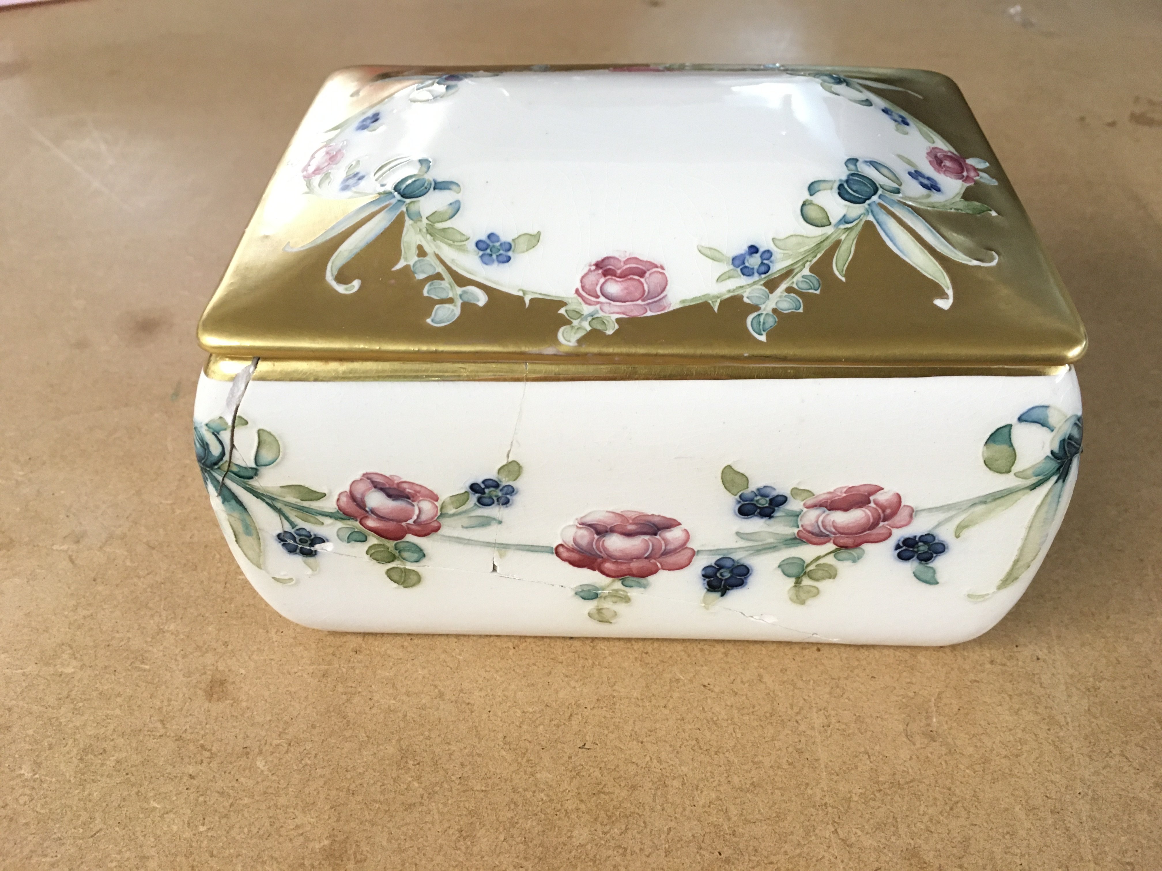 McIntyre Moorcroft ceramic box. 14.5x10.5x7.5cm early 1900s retailed by A la paix 36 Avenue de l opera paris together with a moorcroft pansy saucer green W moorcroft 11.5cm diameter Base has lot of damage but lid is in good condition