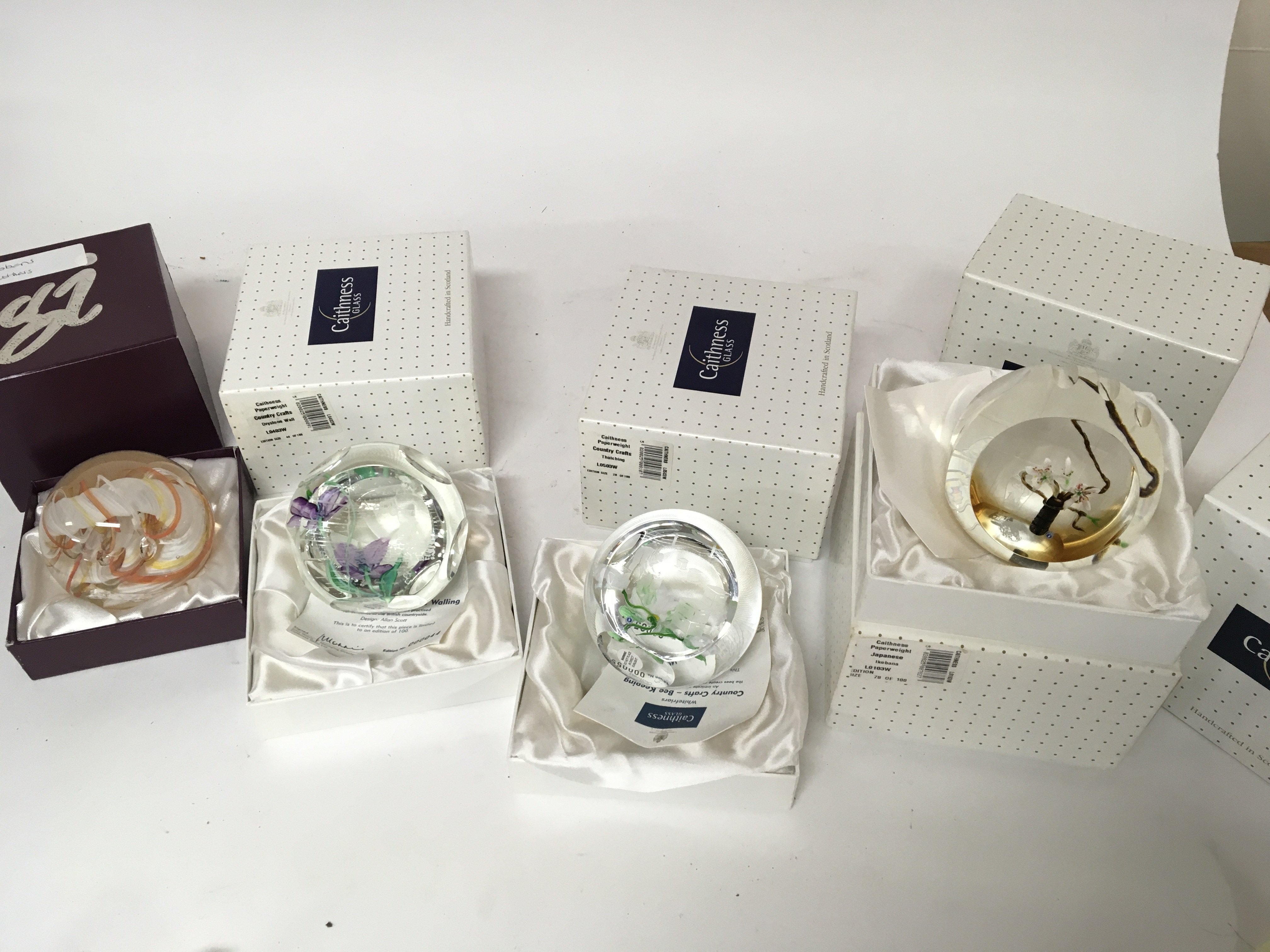 A collection of six boxed Caithness paperweights including Limited editions Japanese tea Ceremony 82/100 Japanese Ikebana 78/100 three country craft paperweights and ruby boxed Ribbons paperweight (6)