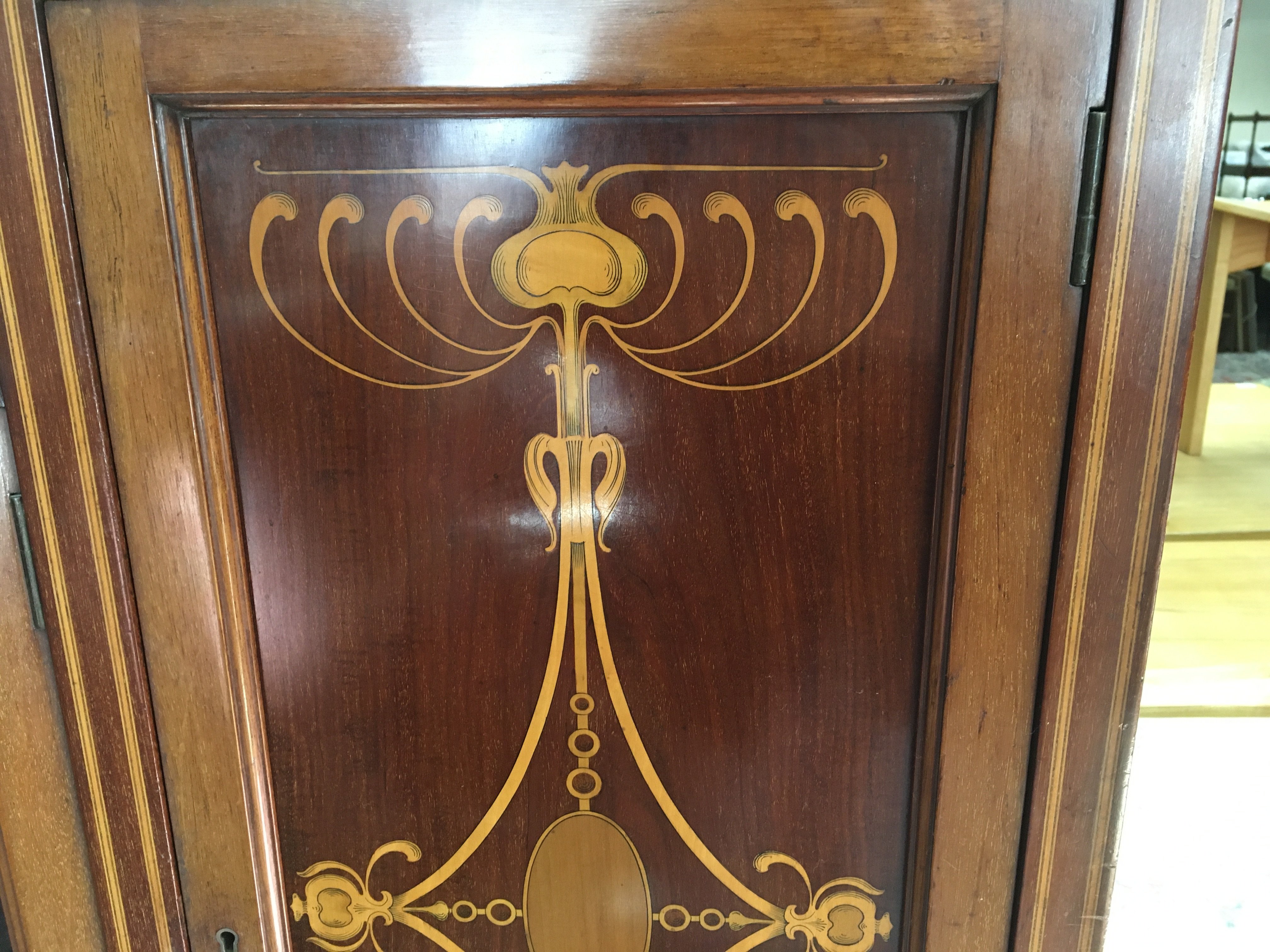 A Edwardian inlaid mahogany display cabinet the rasied mirror back above a pair of glazzed doors flanked by cupboards on square tappering legs . 150 cm x 200 cm .